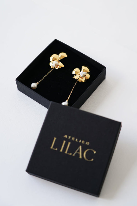 boucles d'oreilles mariage florale avec une perle naturelle dans une boite à bijoux noir avec le logo de la marque atelier lilac