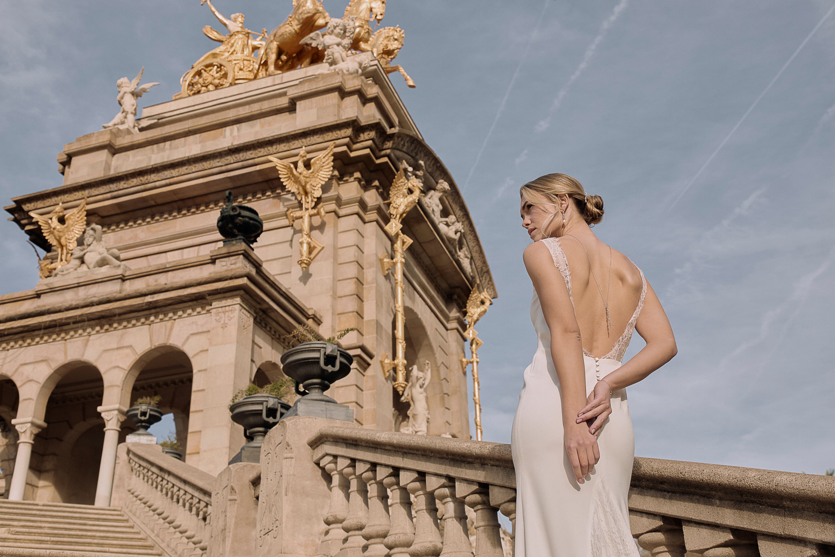 Femme de dos à Barcelone montrant son décolleté de dos et son collier de dos argenté montant des marches avec les mains derrières le dos