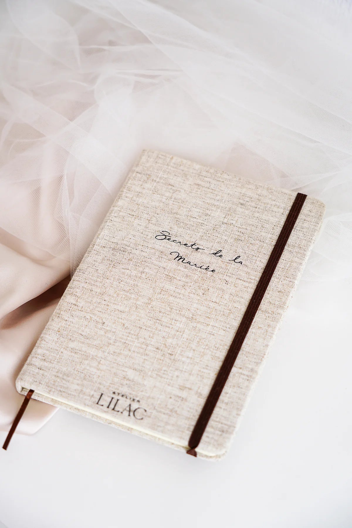 Carnet en tissus beige avec écrit "Secrets de la mariée" et "Atelier Lilac"