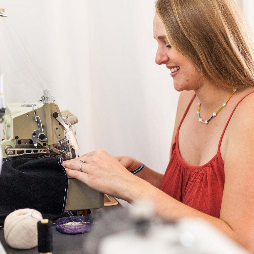 Femme souriante qui coût un vêtement de mariage avec sa machine à coudre