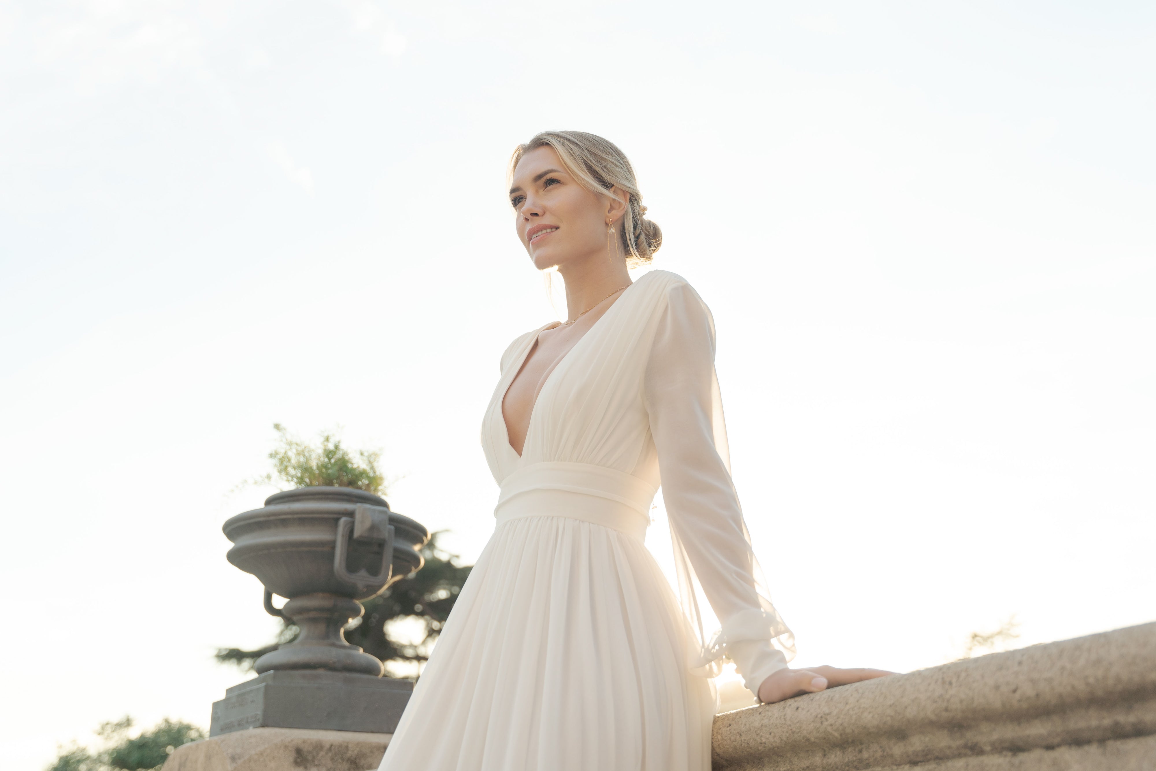 Jeune femme qui sourit avec un chignon de mariage mettant en avant ses boucles d'oreilles pendantes