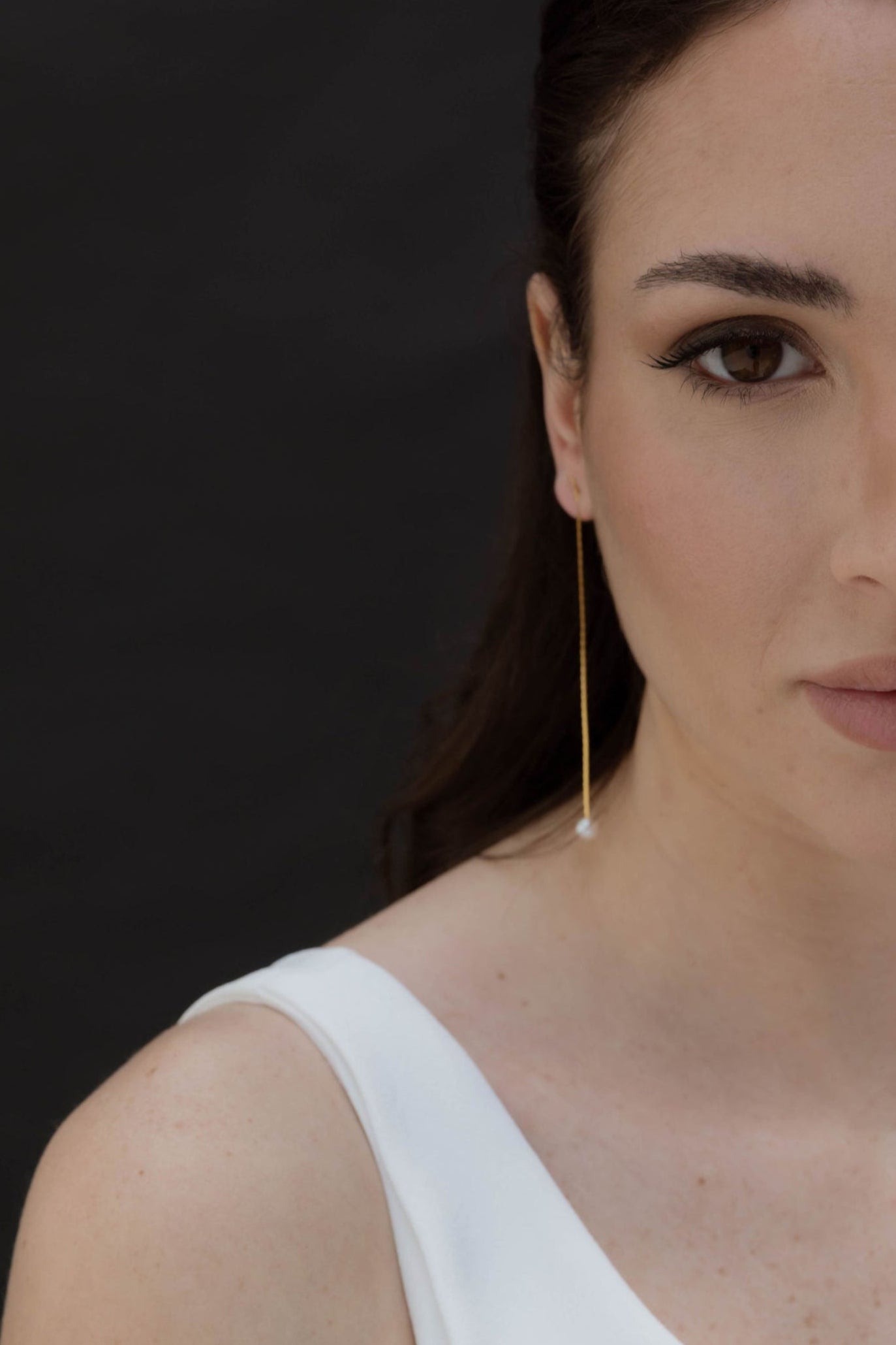 Mariée regardant l'objectif avec sa boucle d'oreille pendante de fête religieuse qui orne son oreille