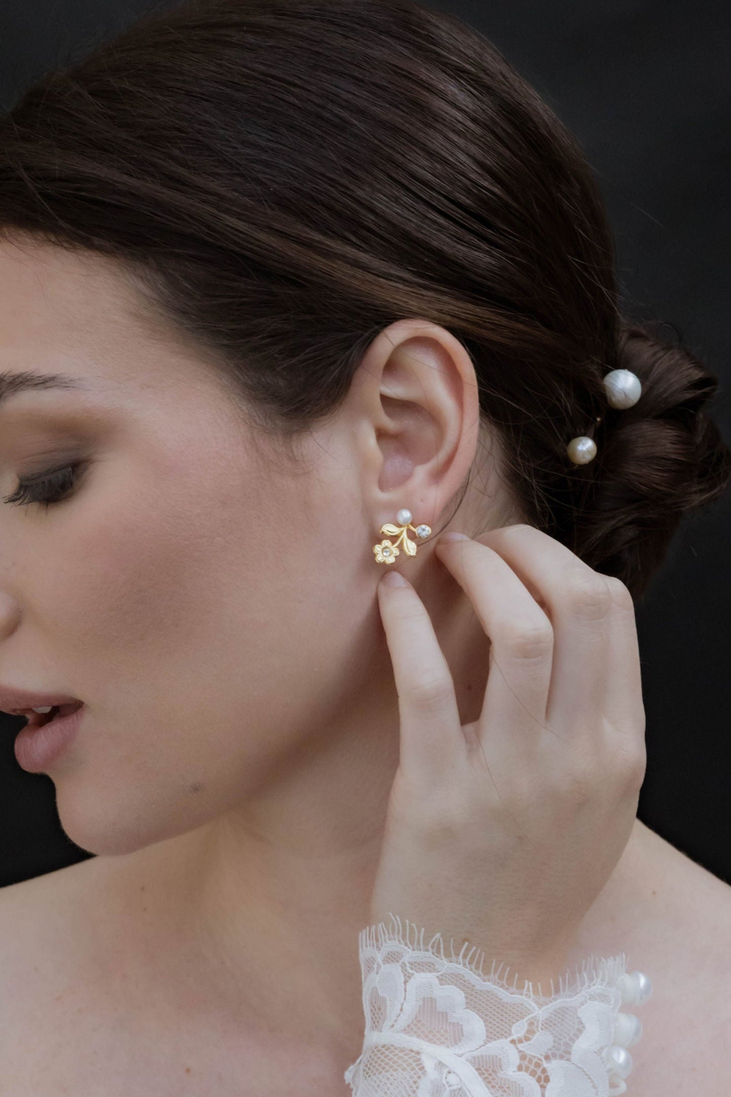 Mariée touchant son oreille portant des boucles d'oreilles de mariage florale avec des perles naturelle et zircons