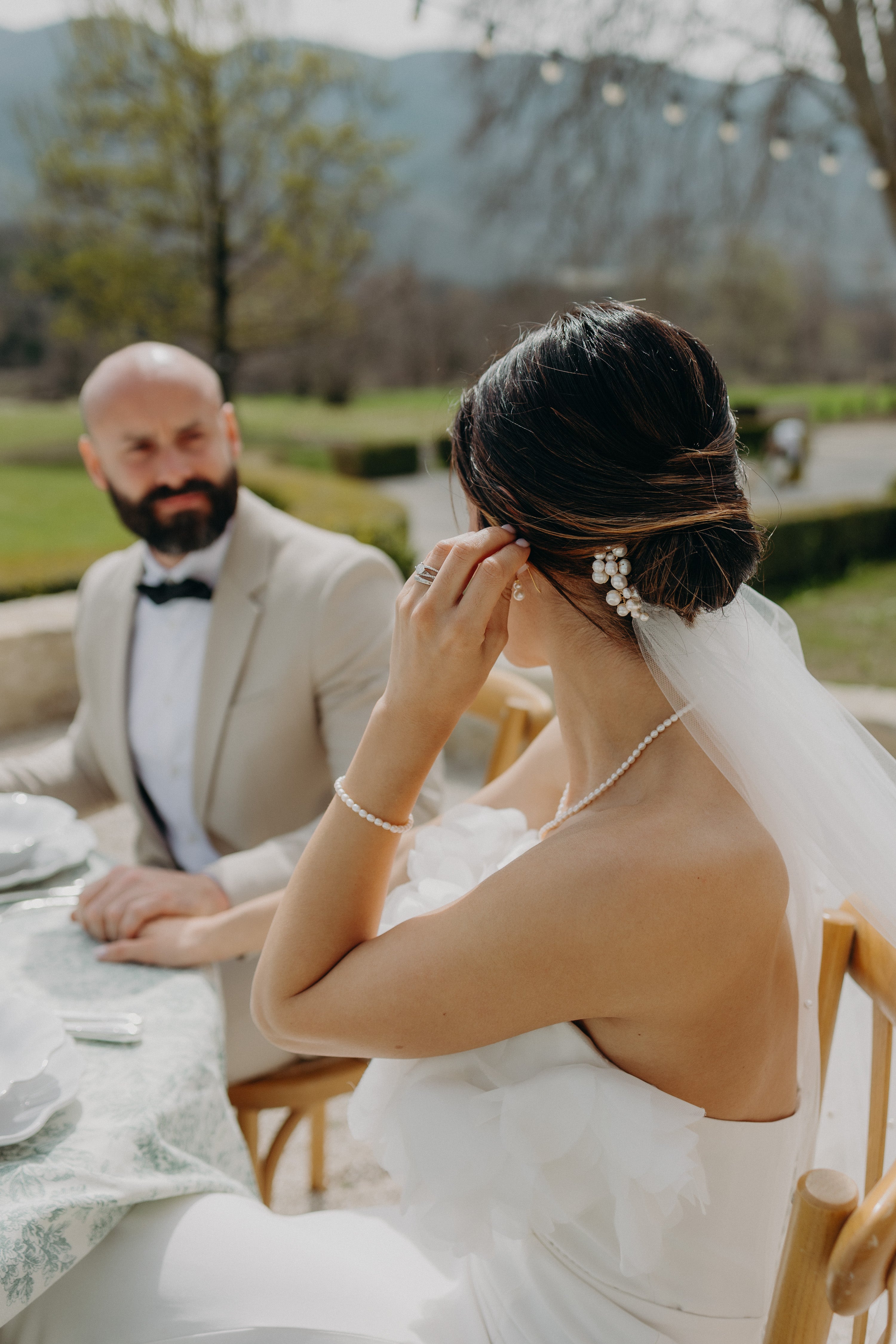 Les mariés souriants, entourés d’une ambiance naturelle et élégante aux tons matcha et olive, pour une inspiration mariage moderne et naturel. La mariée porte des bijoux signés Atelier Lilac, réalisés à la main avec délicatesse et poésie, qui subliment sa tenue et renforcent l’harmonie et le raffinement de cette célébration mémorable.