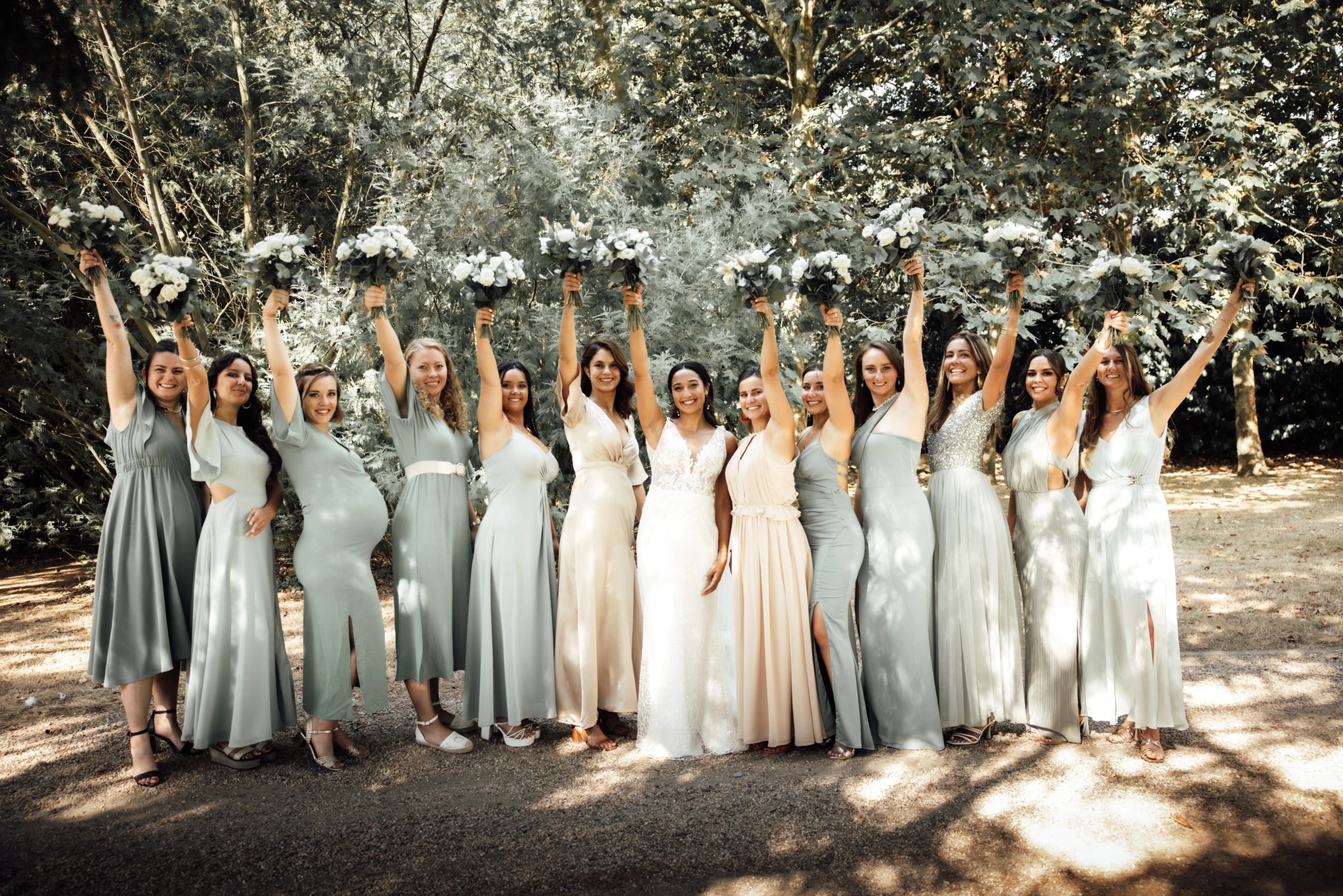 Les demoiselles d'honneurs levant un bouquet vers le ciel autour de la mariée