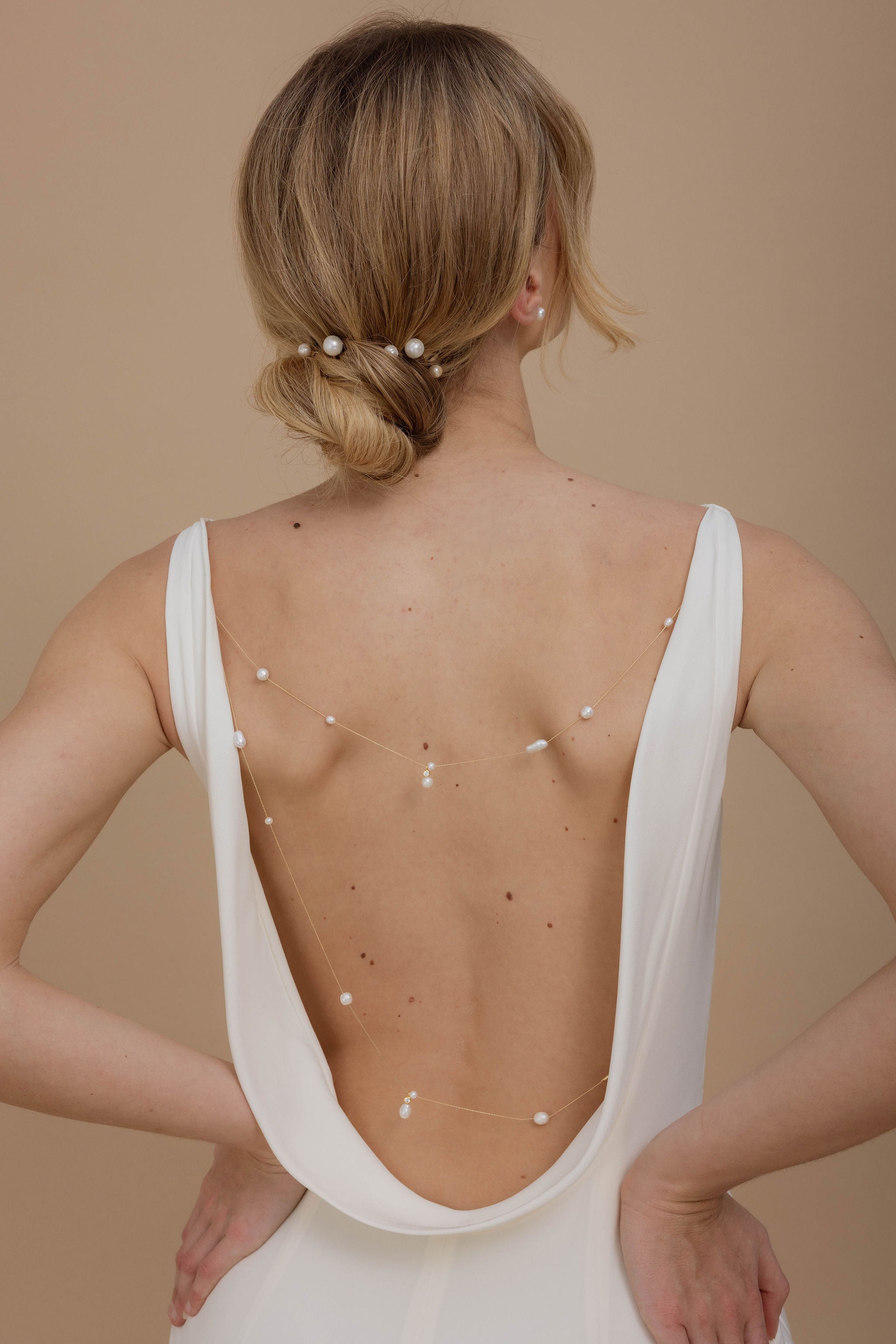 Femme de dos montrant son bijou de dos fait de perles en forme de poire avec une finition bohème pour mariée