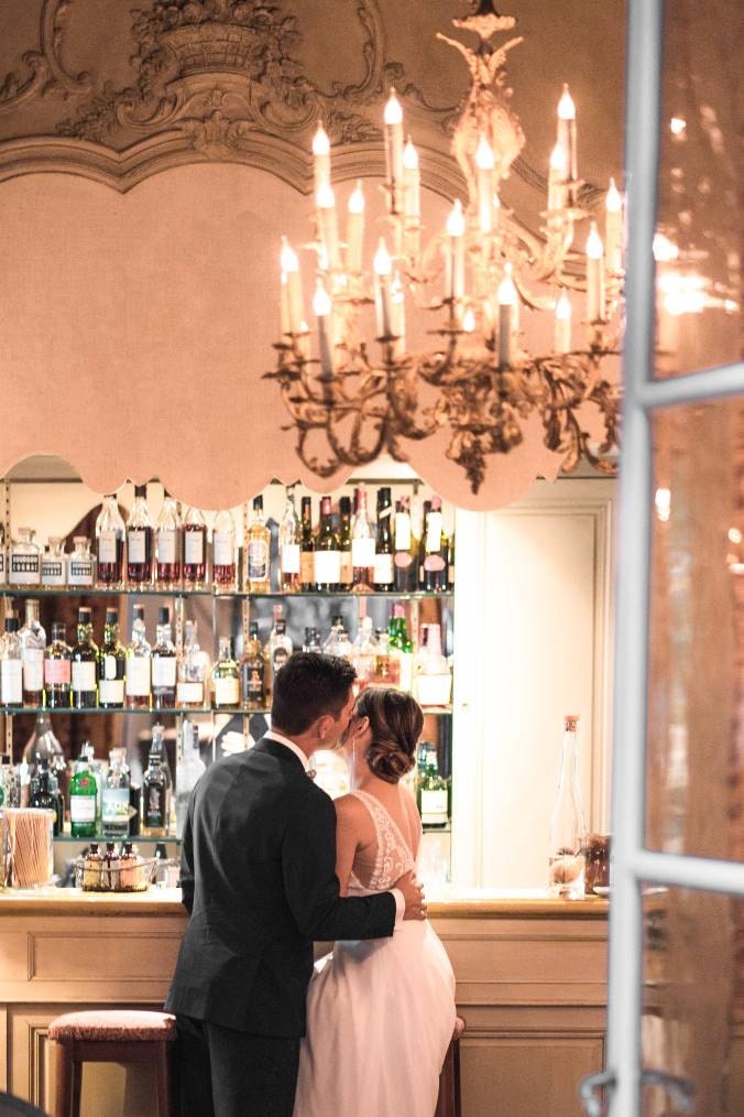 Femme et homme de dos qui s'enlacent devant le bar dans des tenues de mariage