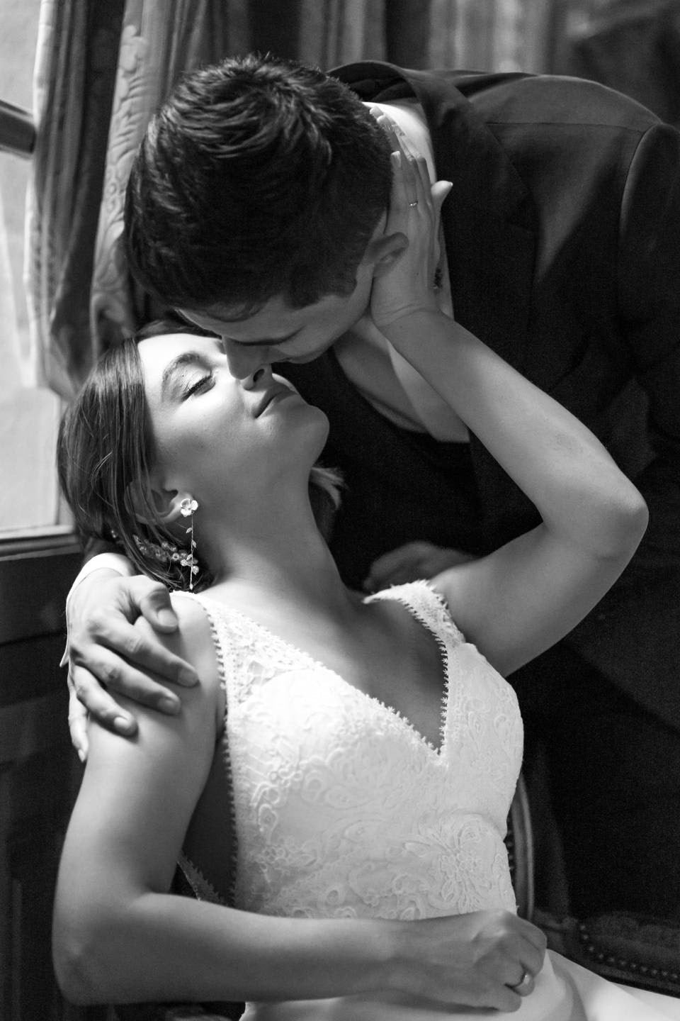 Femme tenant le cou de son homme qui se penche pour l'embrasser pendant le photo shoot de leurs mariage