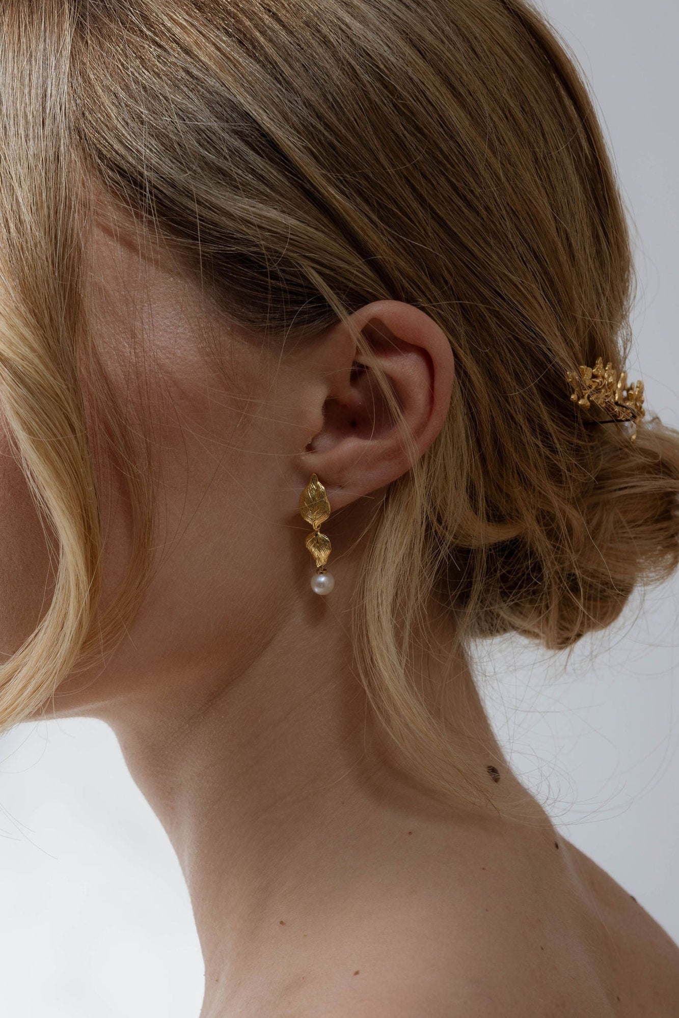 Femme de profil montrant son oreille orné d'une boucle de cérémonie en forme de fleur avec une perle naturelle