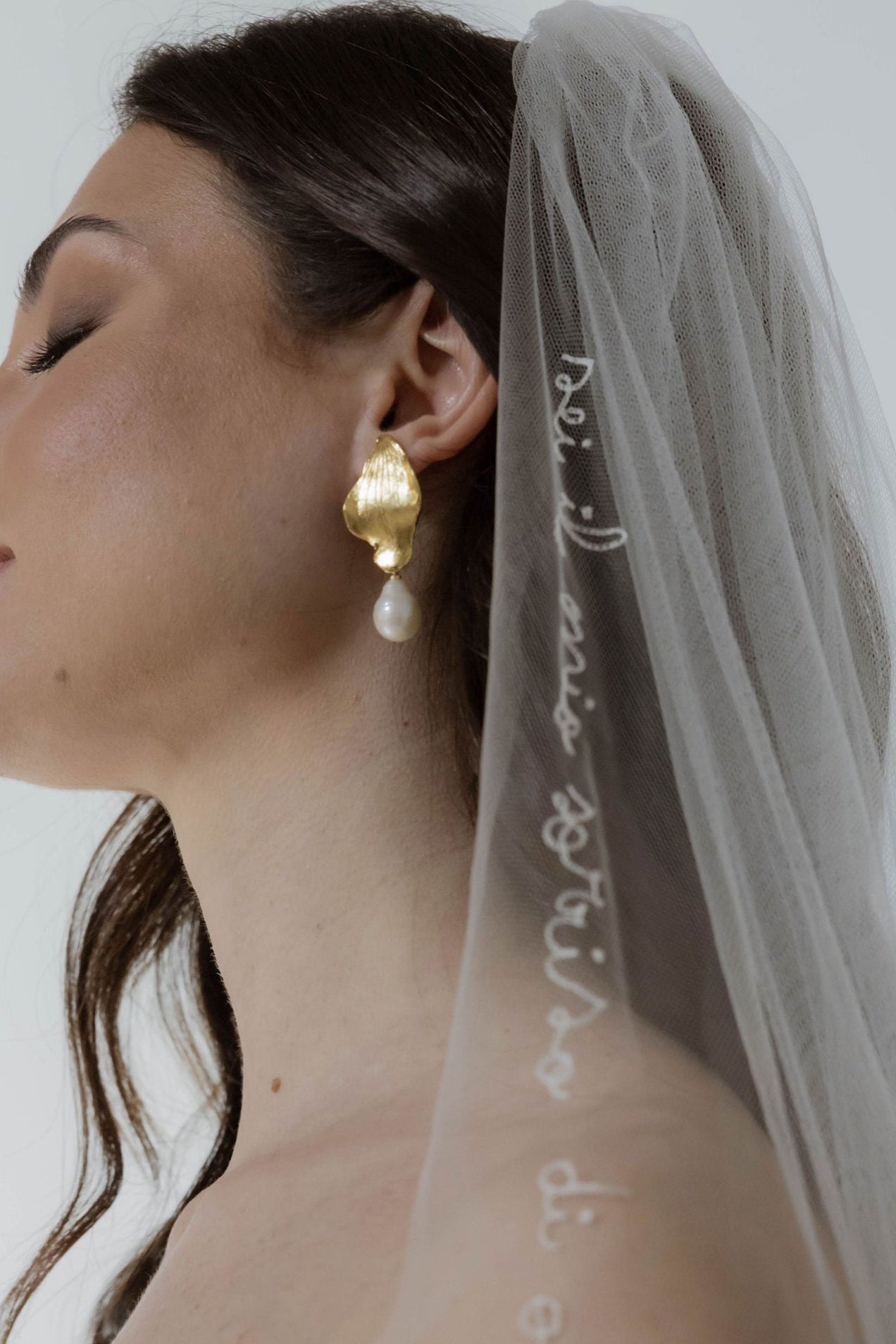 Femme de profil portant un voile de mariage ainsi que ses boucles d'oreilles en forme de feuille pour les cérémonie religieuse