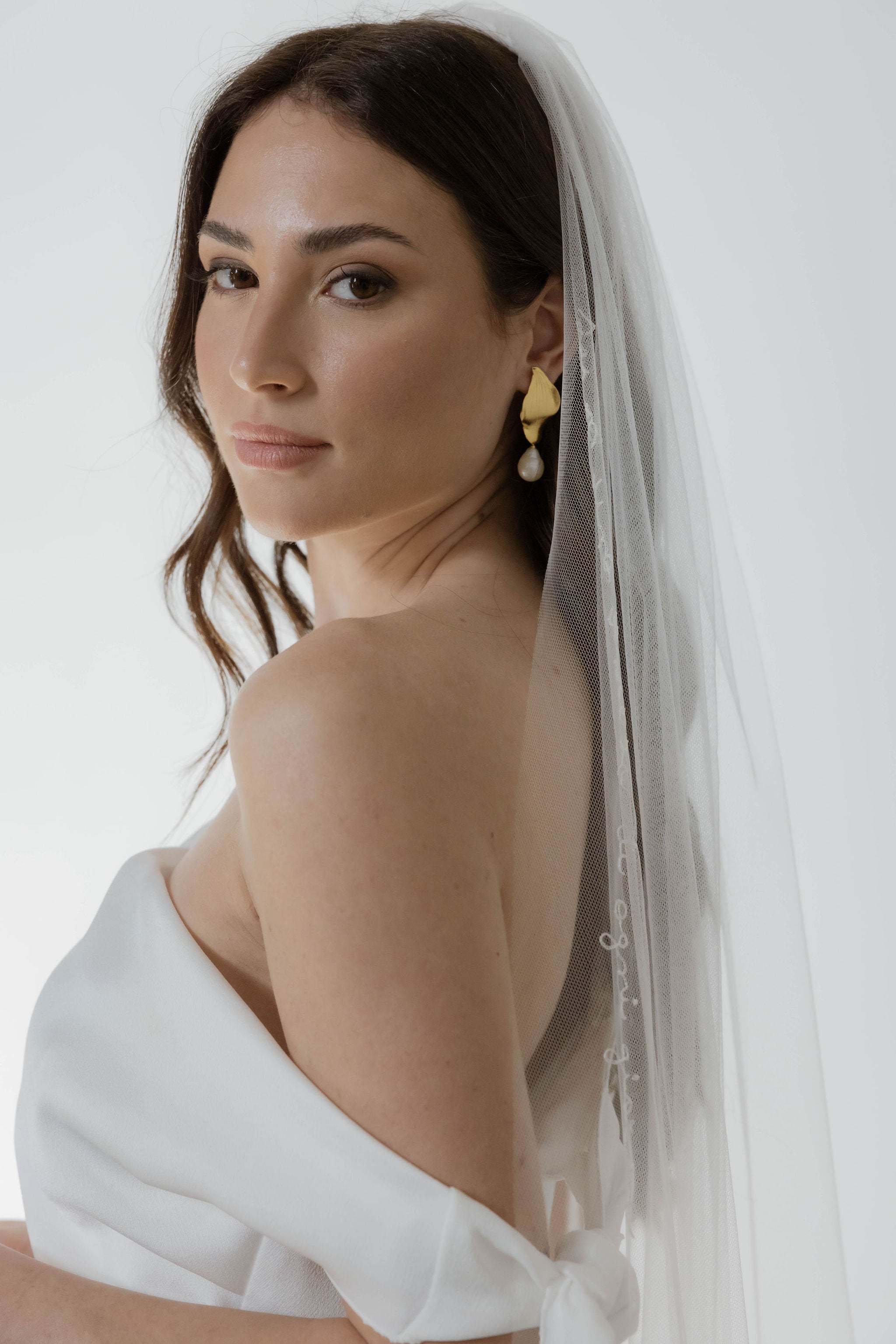 Femme de profil avec une paire de boucles d'oreilles fleuri en forme de fleur avec une perle baroque naturelle