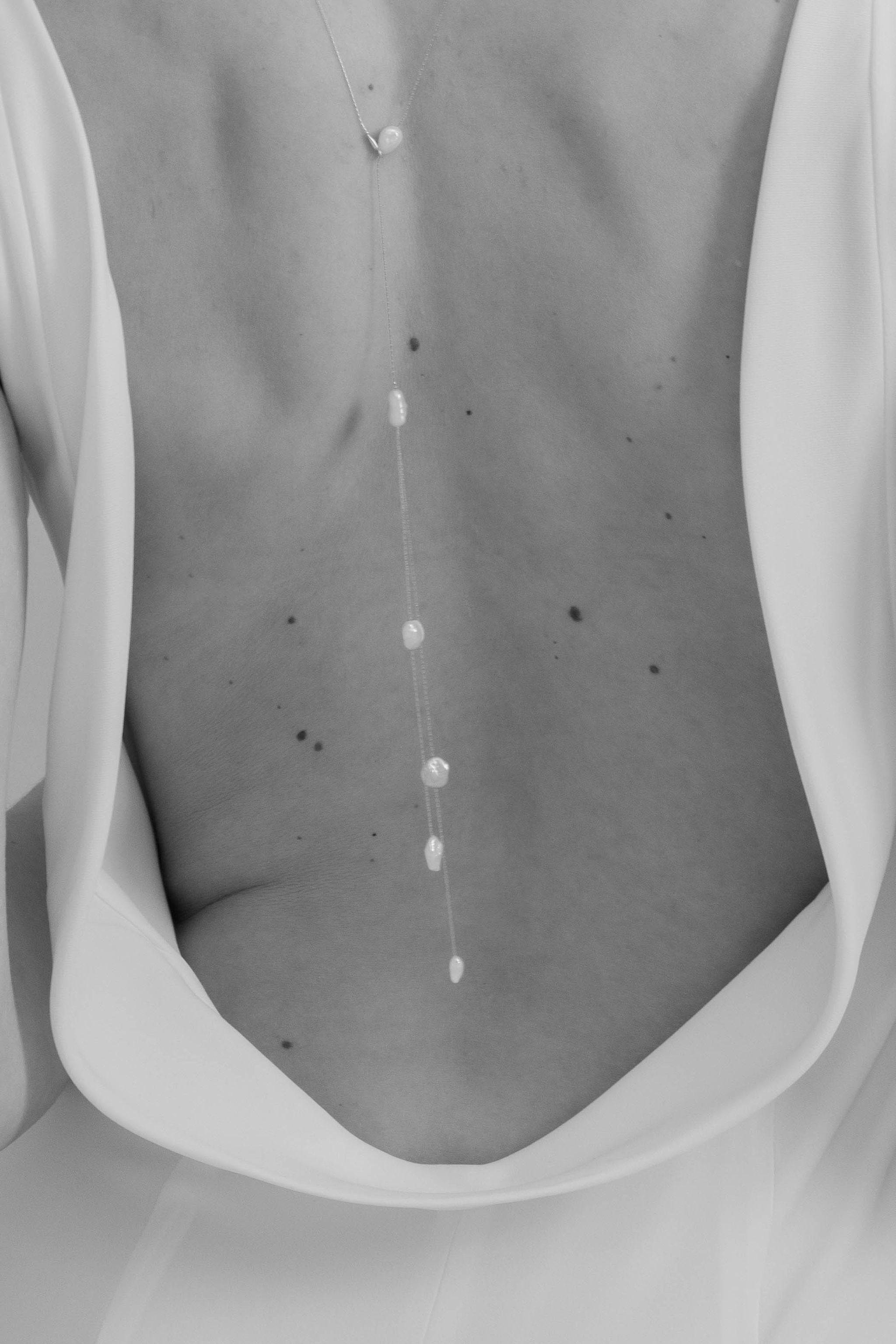 Focus sur le dos d'une mariée portant un accessoire de dos avec des perles en forme bohème