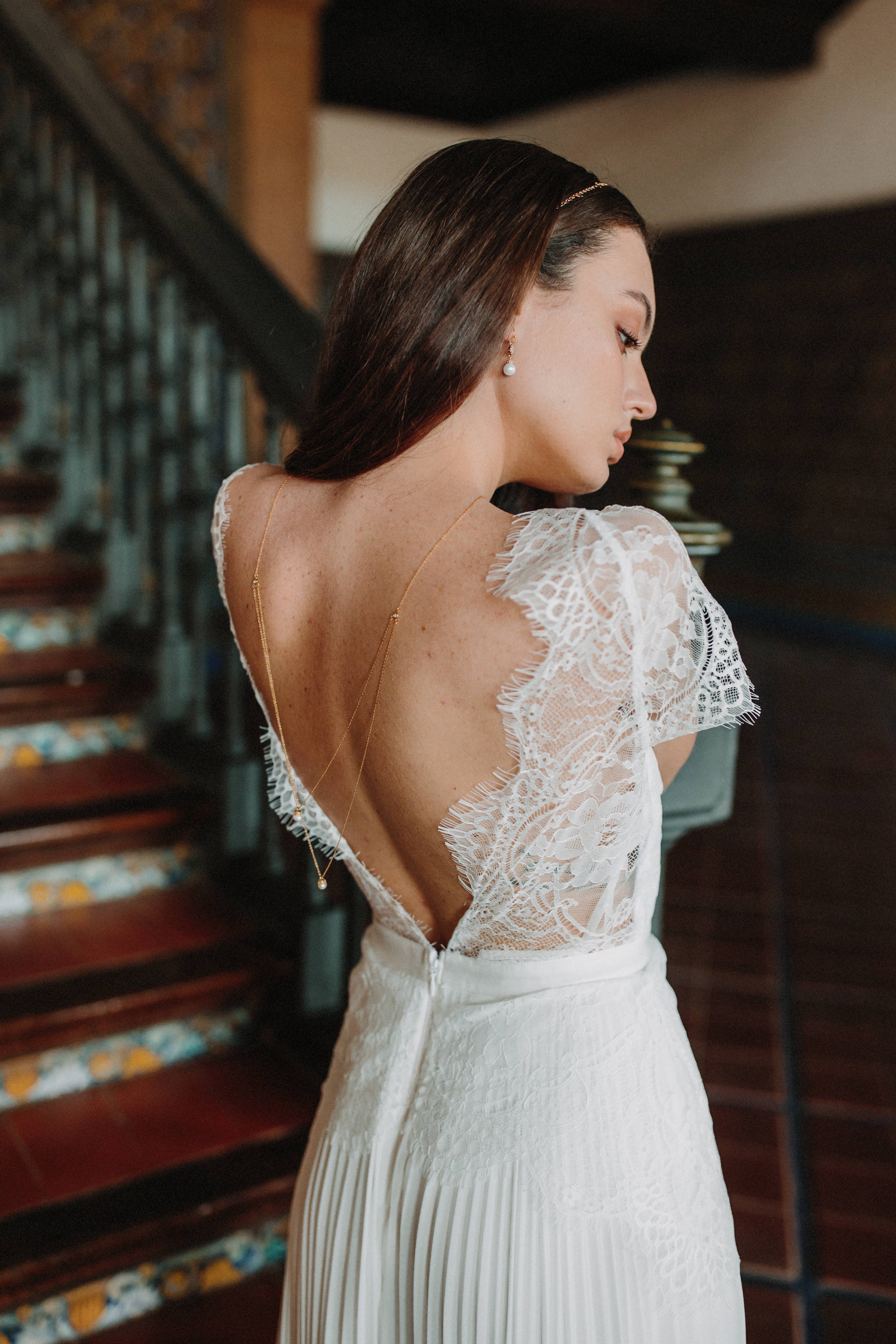 Mariée portant un collier de dos à doubles chaînes dorées avec une perle à chaque extrémité, boucles d'oreilles assorties