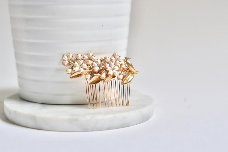 petit peigne de cheveux mariage dans le style floral romantique avec des fleurs blanche et une feuille en or sur un pot de fleur blanc