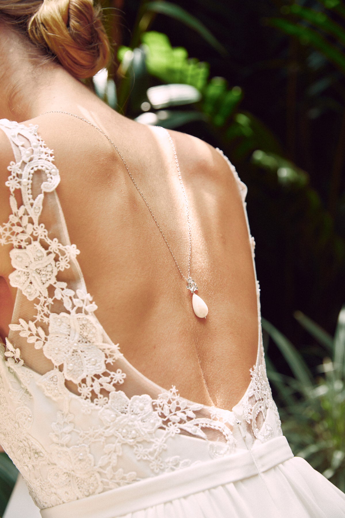 mariée dans la nature portant collier de dos avec un chignon bas