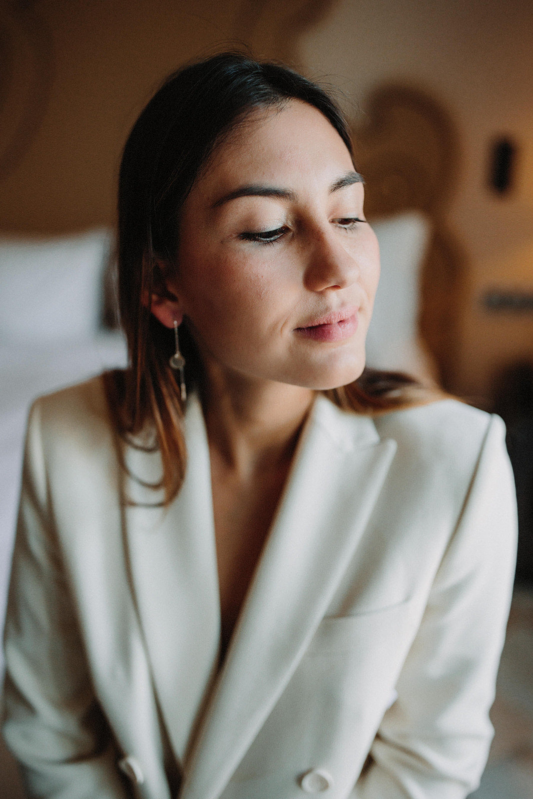 demoiselle d'honneur en blazer blanc portant des boucles d'oreilles minimaliste