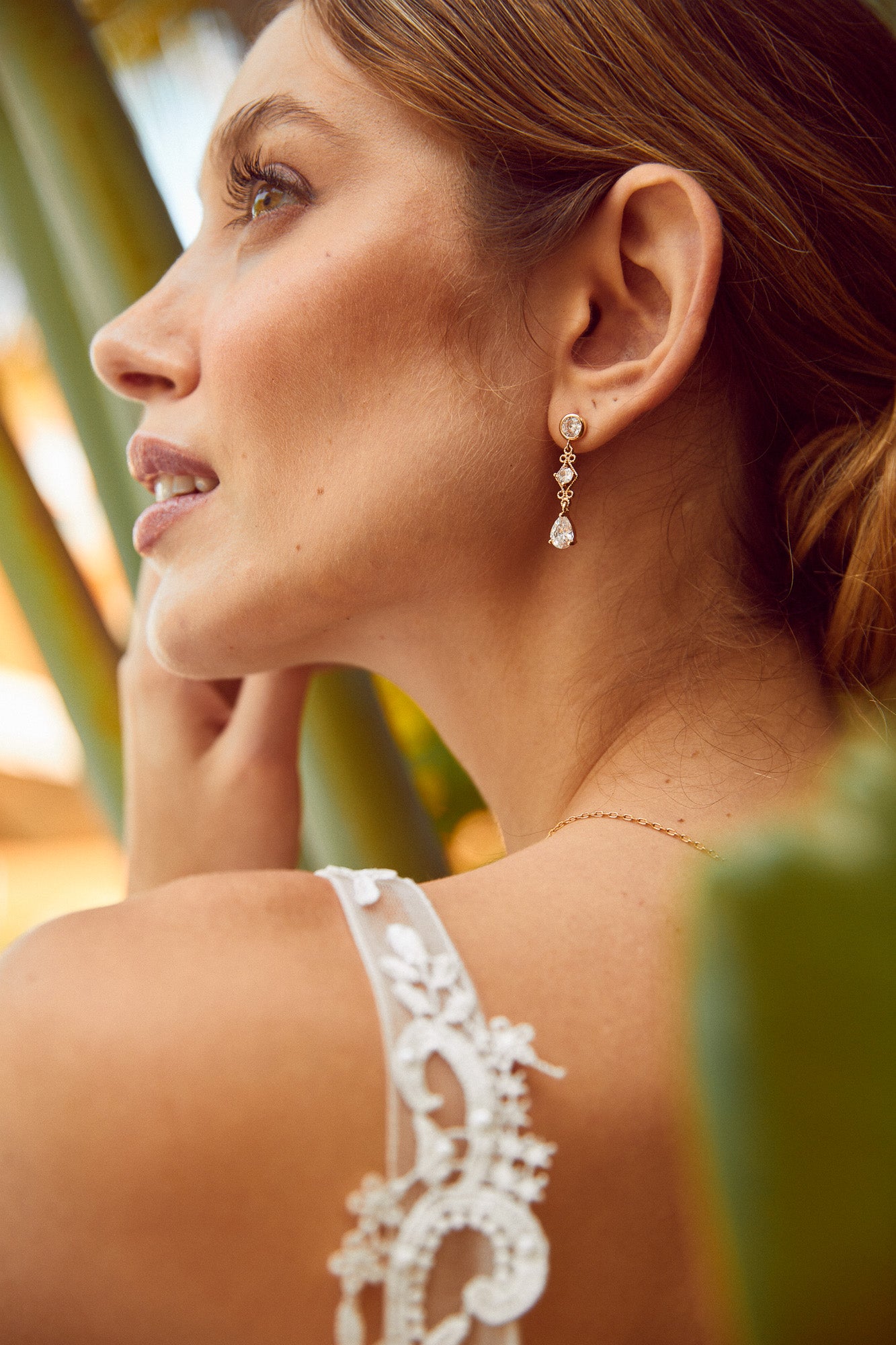 mariée dans le jardin du lieu de son mariage portant des boucles d'oreilles pendantes avec des zircons style romantique bohème
