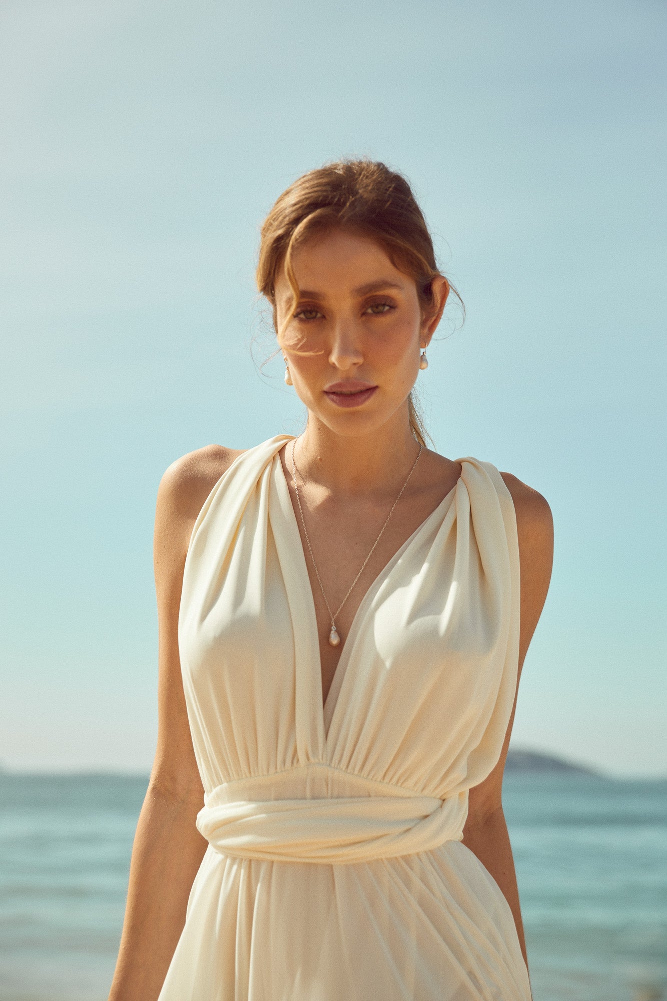 Collier décolleté de mariée sur la plage avec une coiffure en queue de cheval base