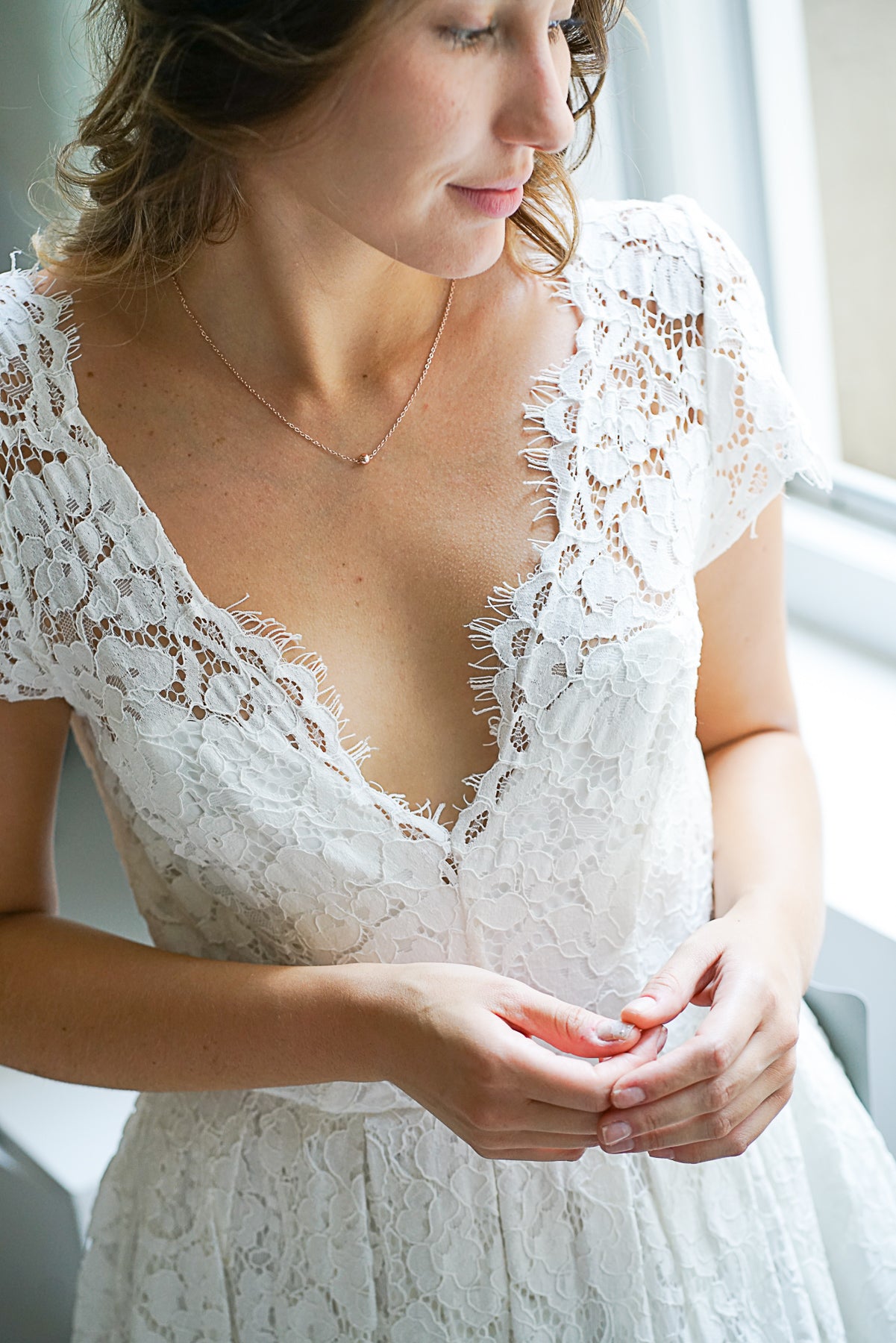 mariée portant un collier avec un pendentif bille en or rose et une robe en dentelle