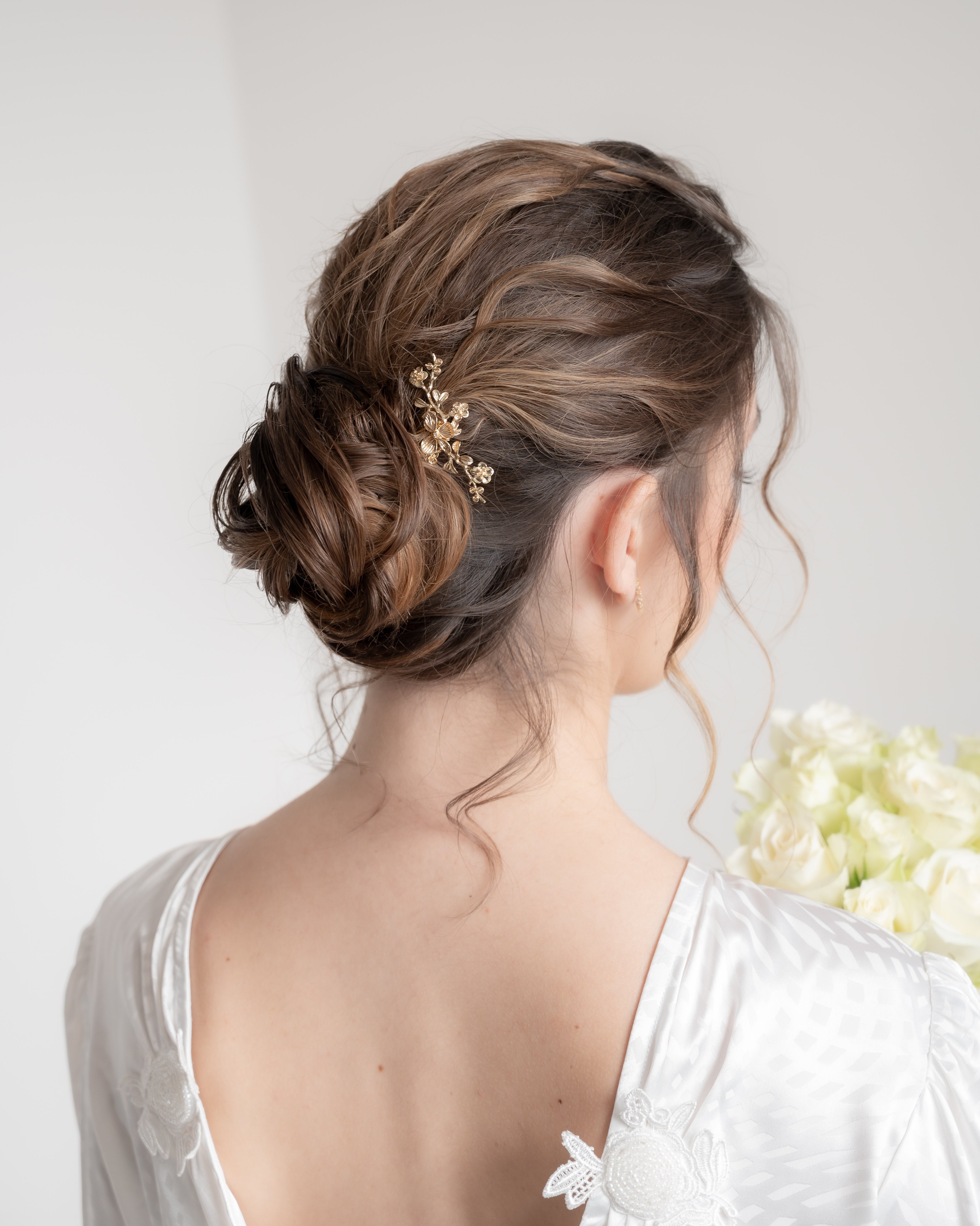 Mariée avec chignon coiffé décoiffé et pic à cheveux doré fleuri