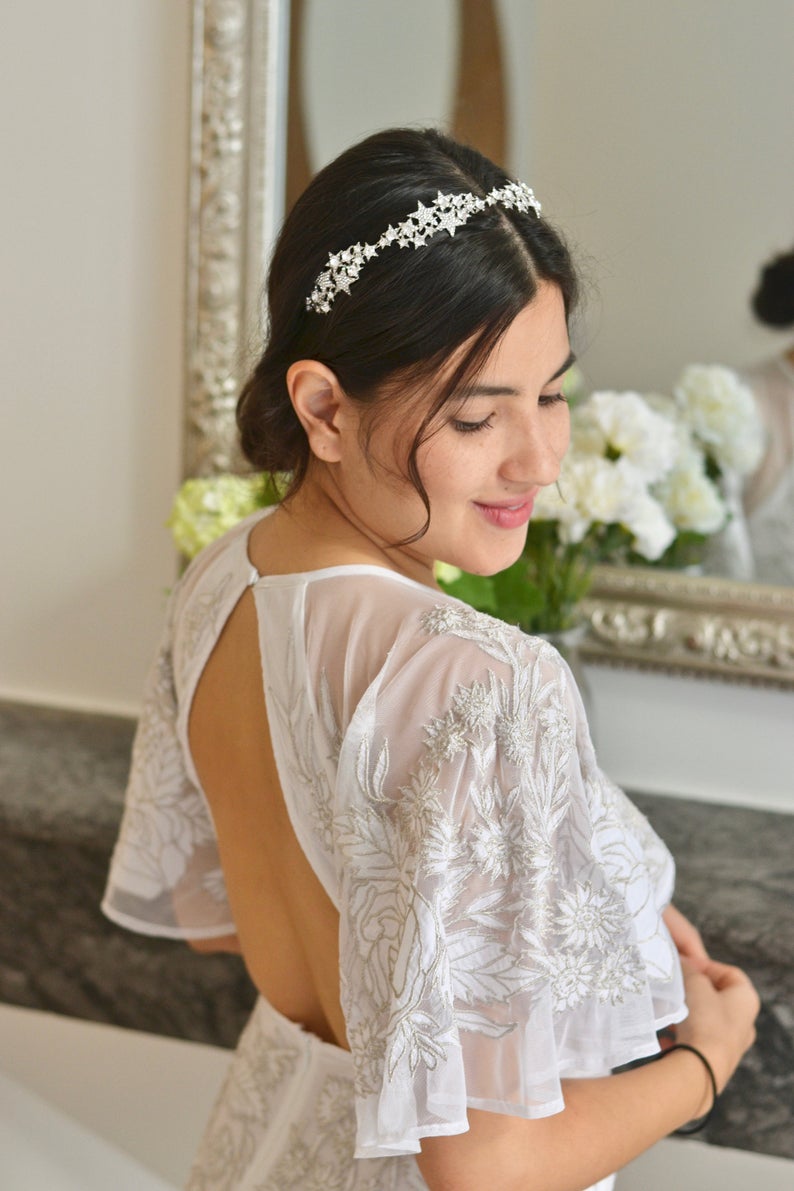 mariée de dos avec sa coiffure de mariage en chignon bas et un headband étoiles
