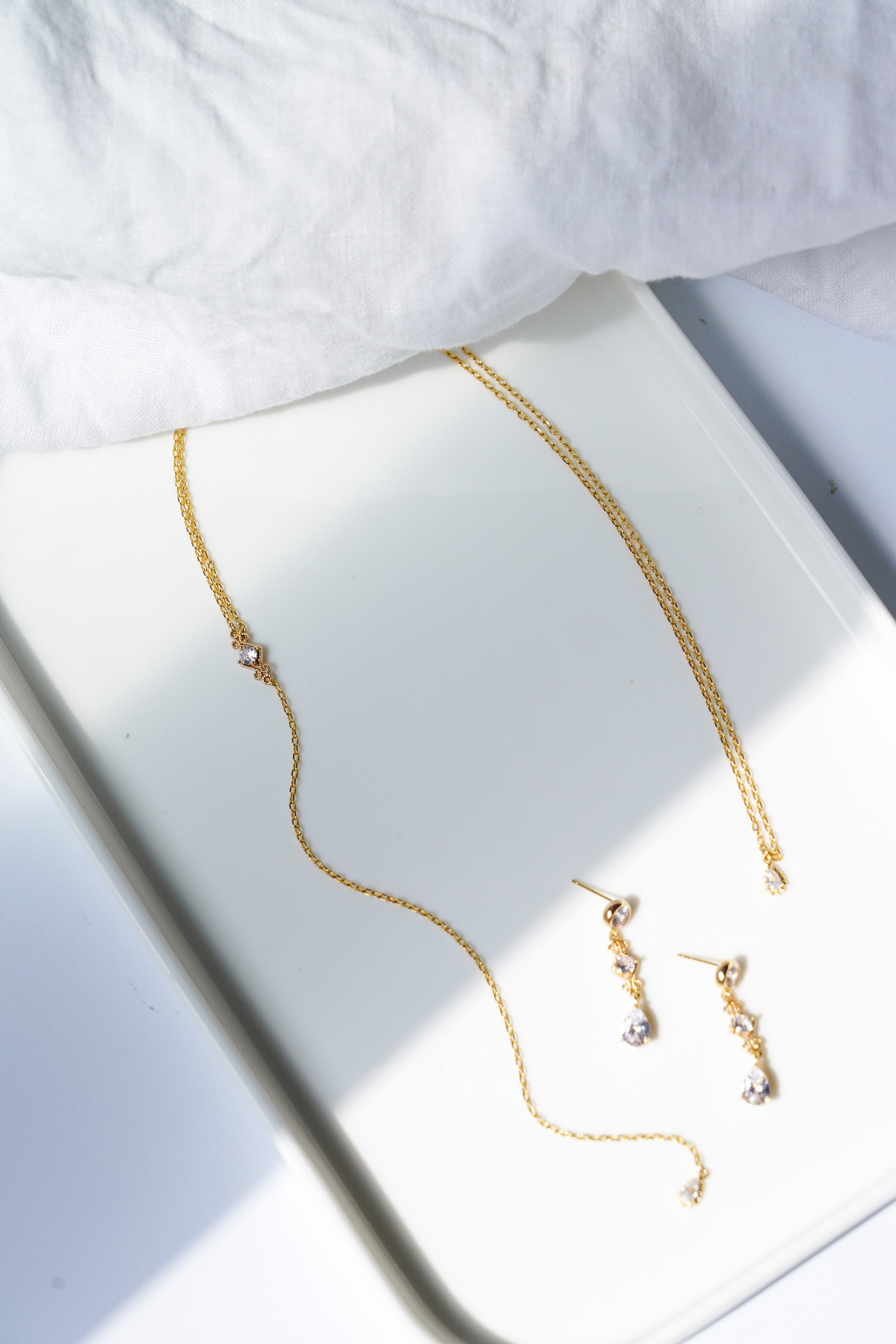 collier de dos et boucles d'oreilles en cristaux style vintage bohème posé sur un plateau blanc