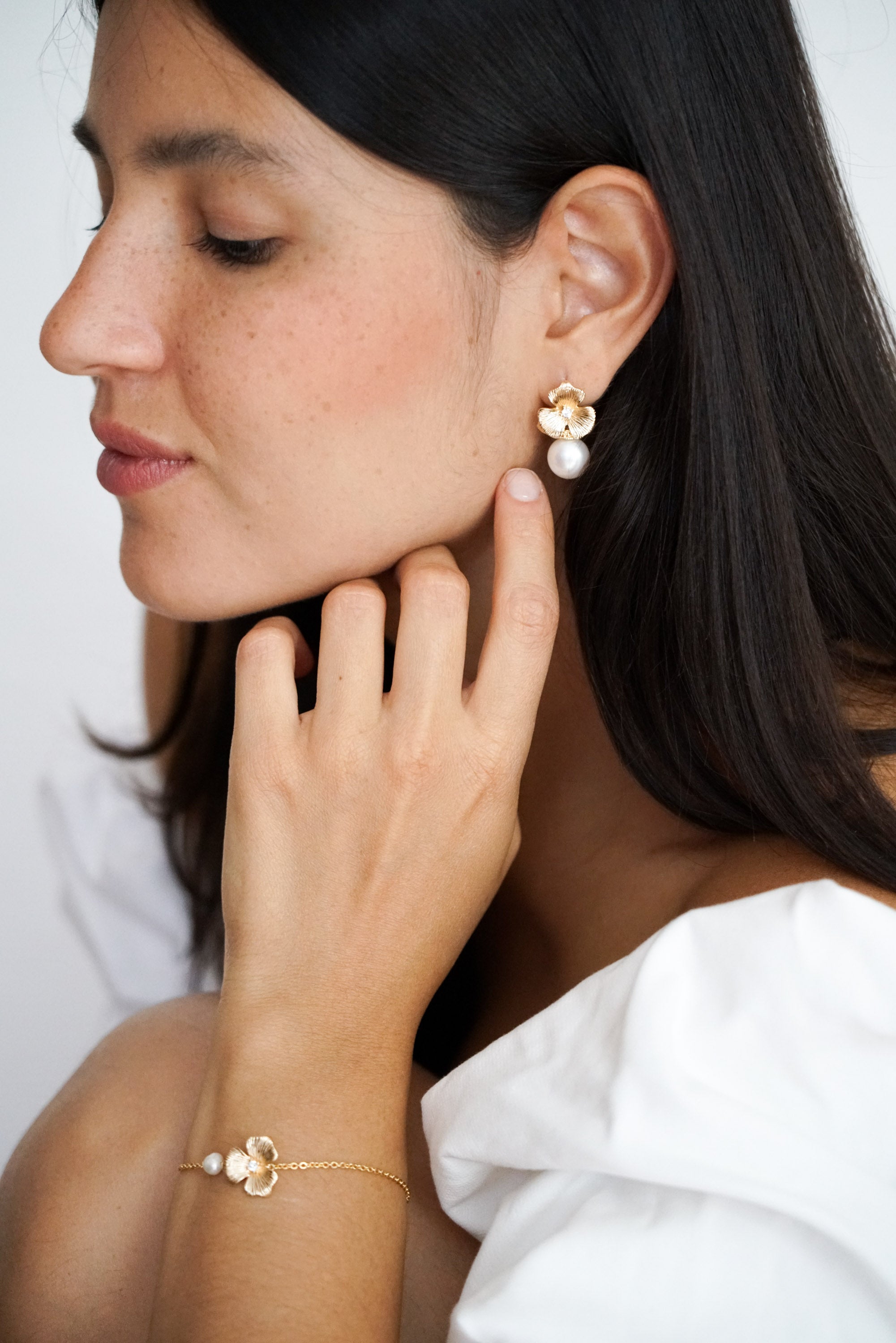 Mariée portant des boucles d'oreilles et un bracelet faits d'une fleur or et d'une perle naturelle