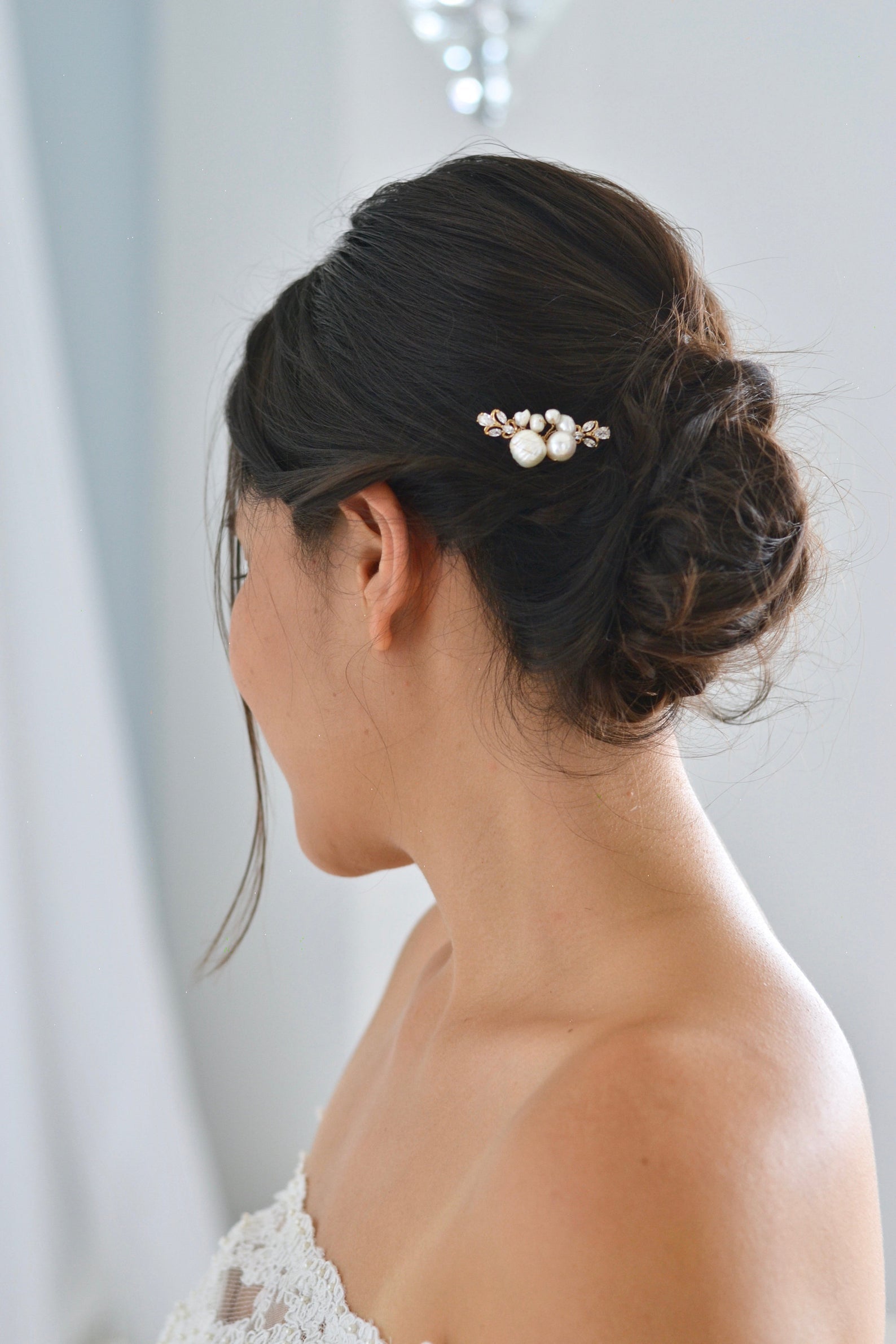 Mariée avec un beau chignon bohème portant un pic à cheveux à perles et cristaux