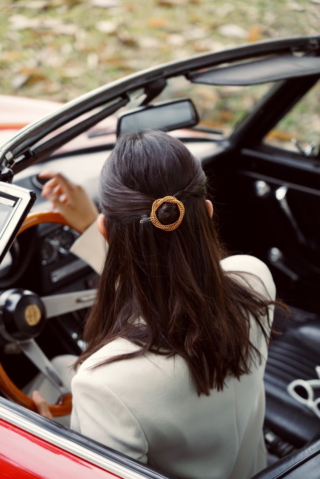 Femme au volant d'une voiture portant un double cercle torsadé doré