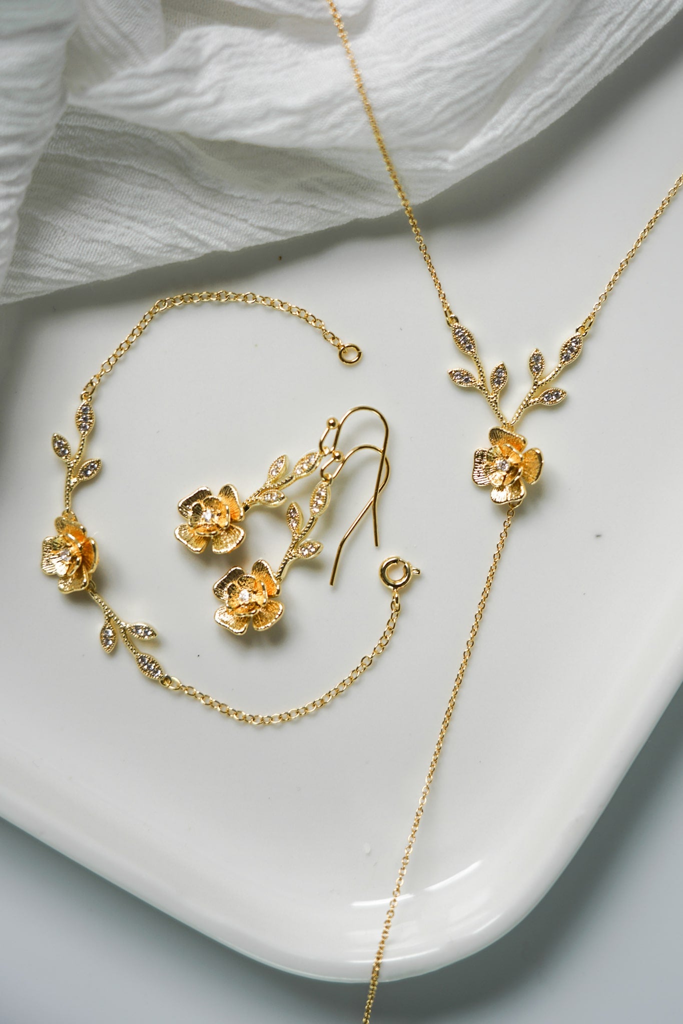 bijoux de mariage floral et bohème en or sur un plateau blanc