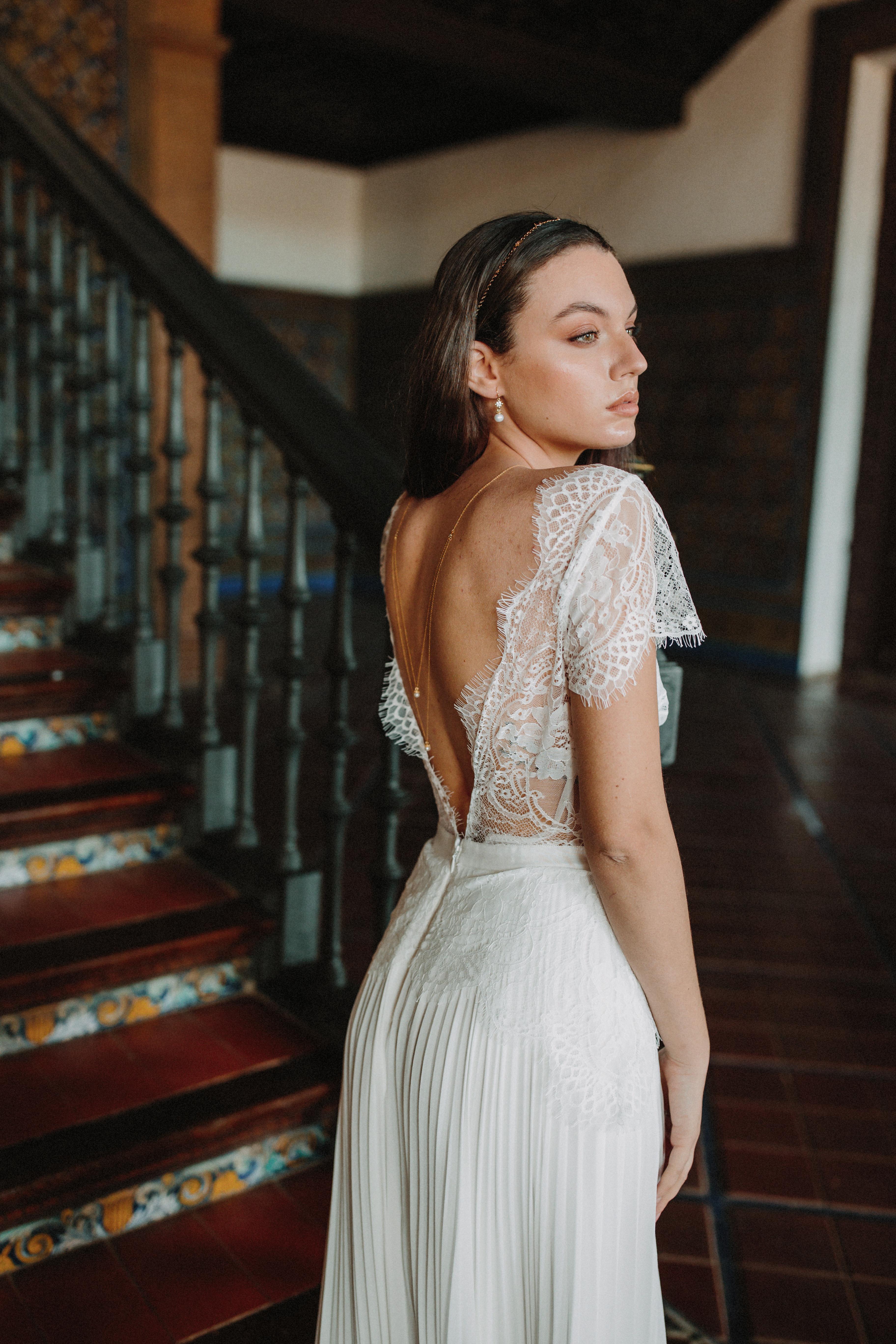 Mariée portant un collier de dos à doubles chaînes dorées avec une perle à chaque extrémité, boucles d'oreilles assorties au pied d'escaliers