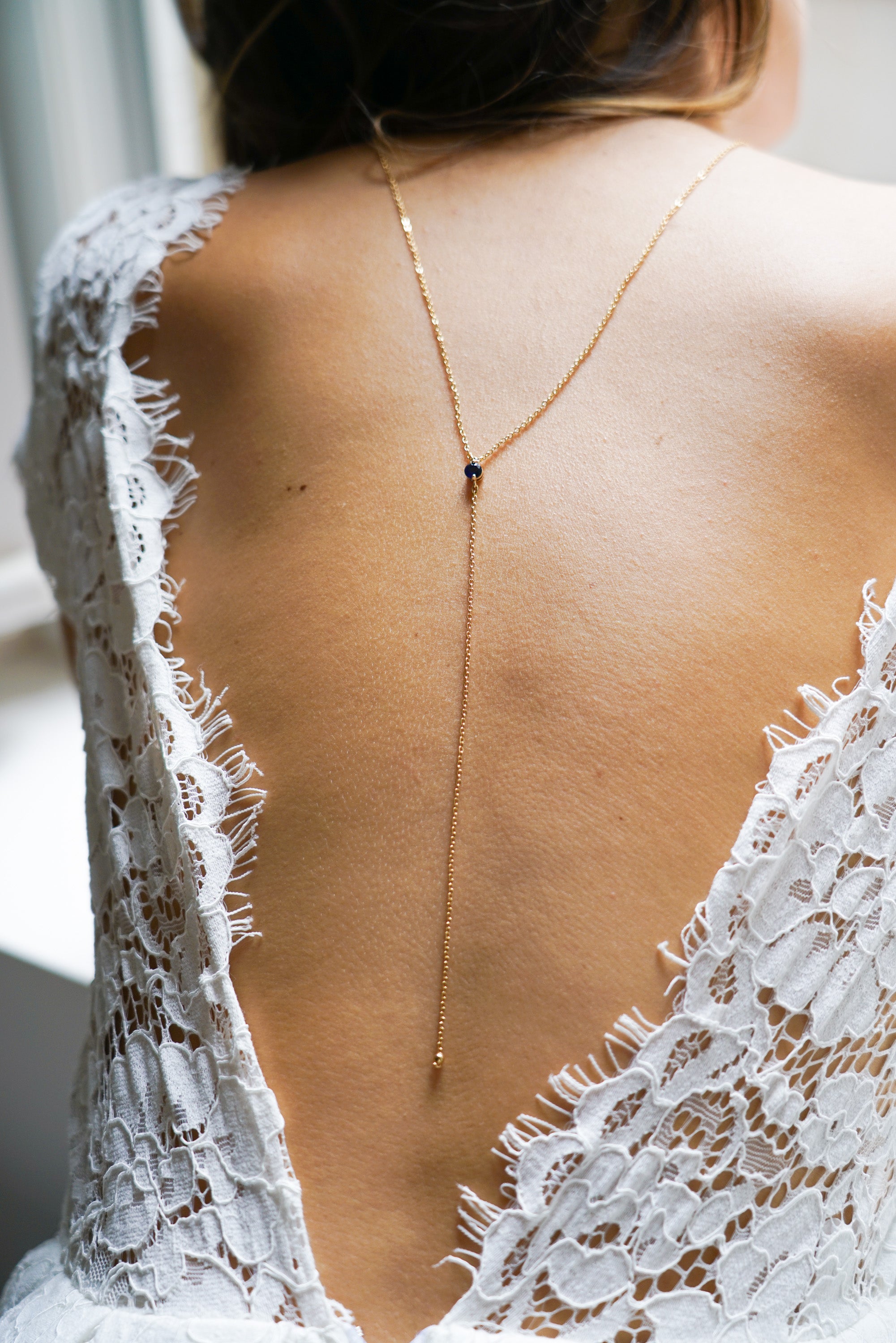 collier de dos pour mariage avec une pierre naturelle bleu porté par une mariée