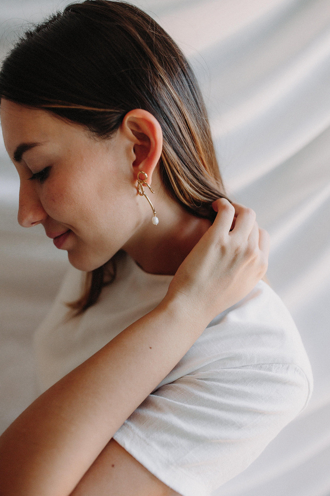boucles d'oreilles mariage en argent en forme de noeud avec une perle porté par la mariée