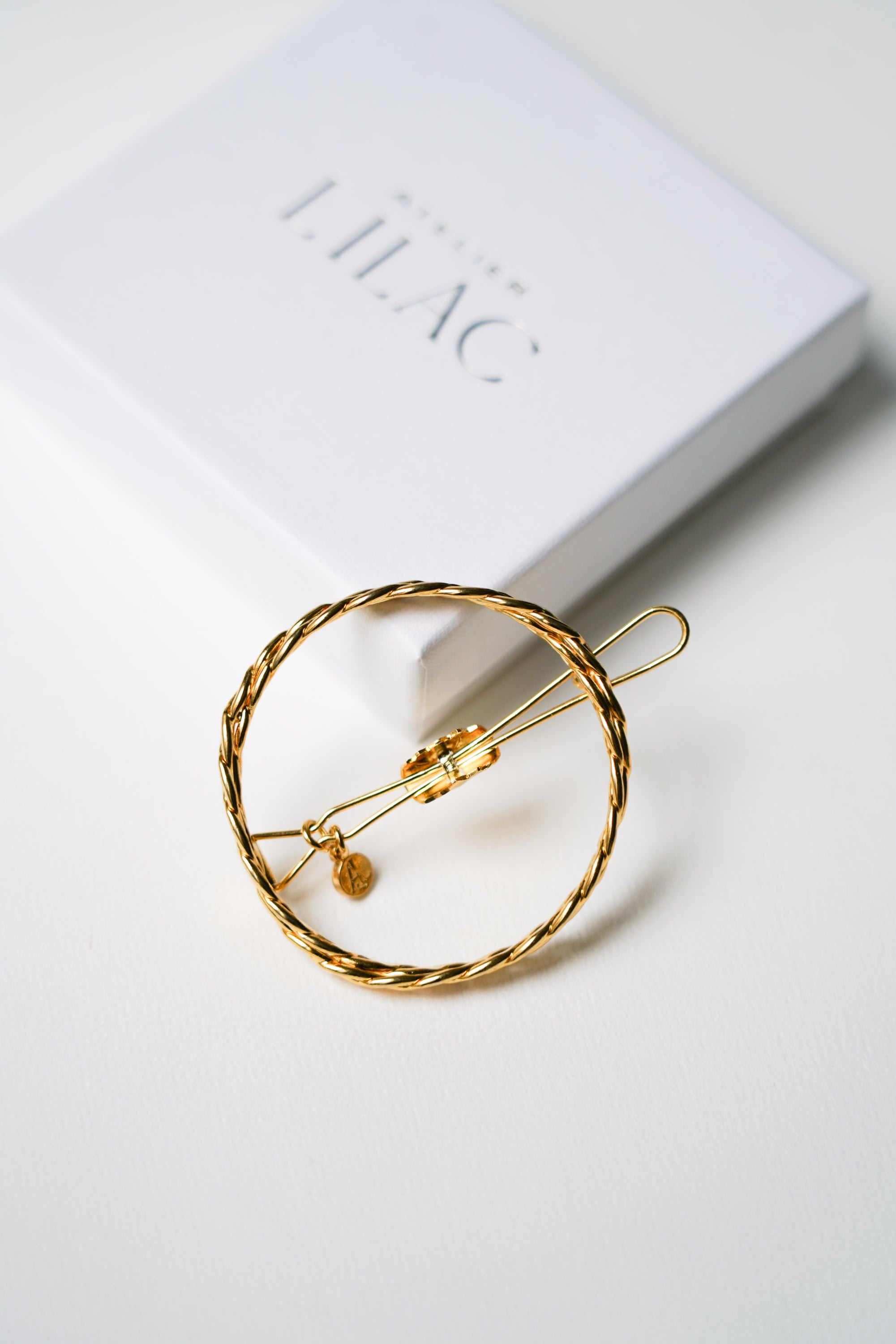 barrette de mariage en or tressé sur un fond blanc avec sa boîte de rangement