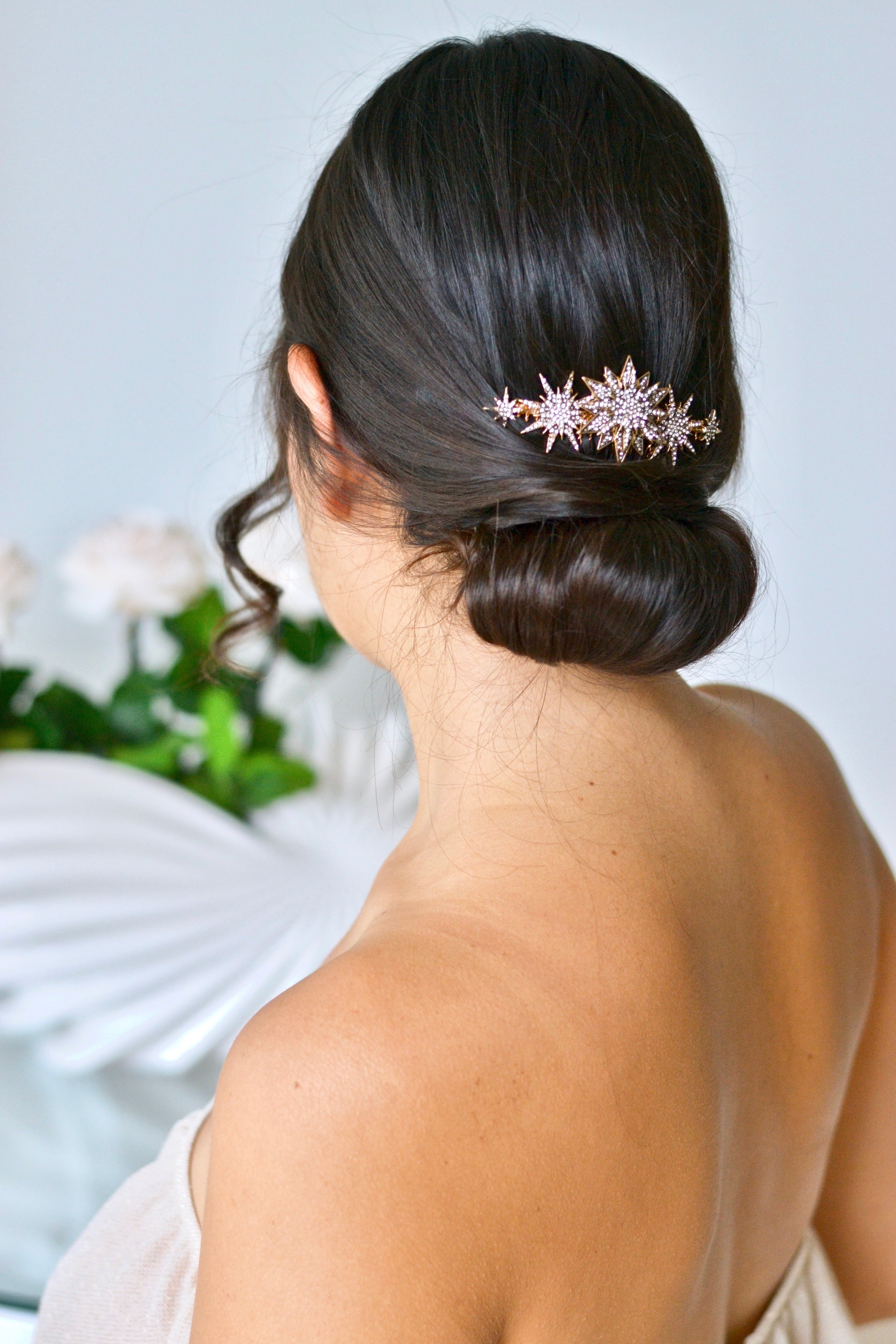 peigne céleste avec des étoiles de différentes tailles dans un chignon de mariée en robe bustier