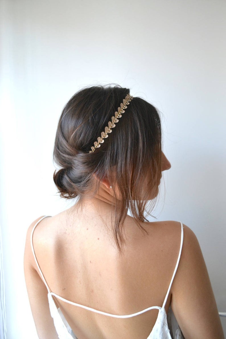 mariée brune avec un chignon bas et un headband en forme de fleurs cousus