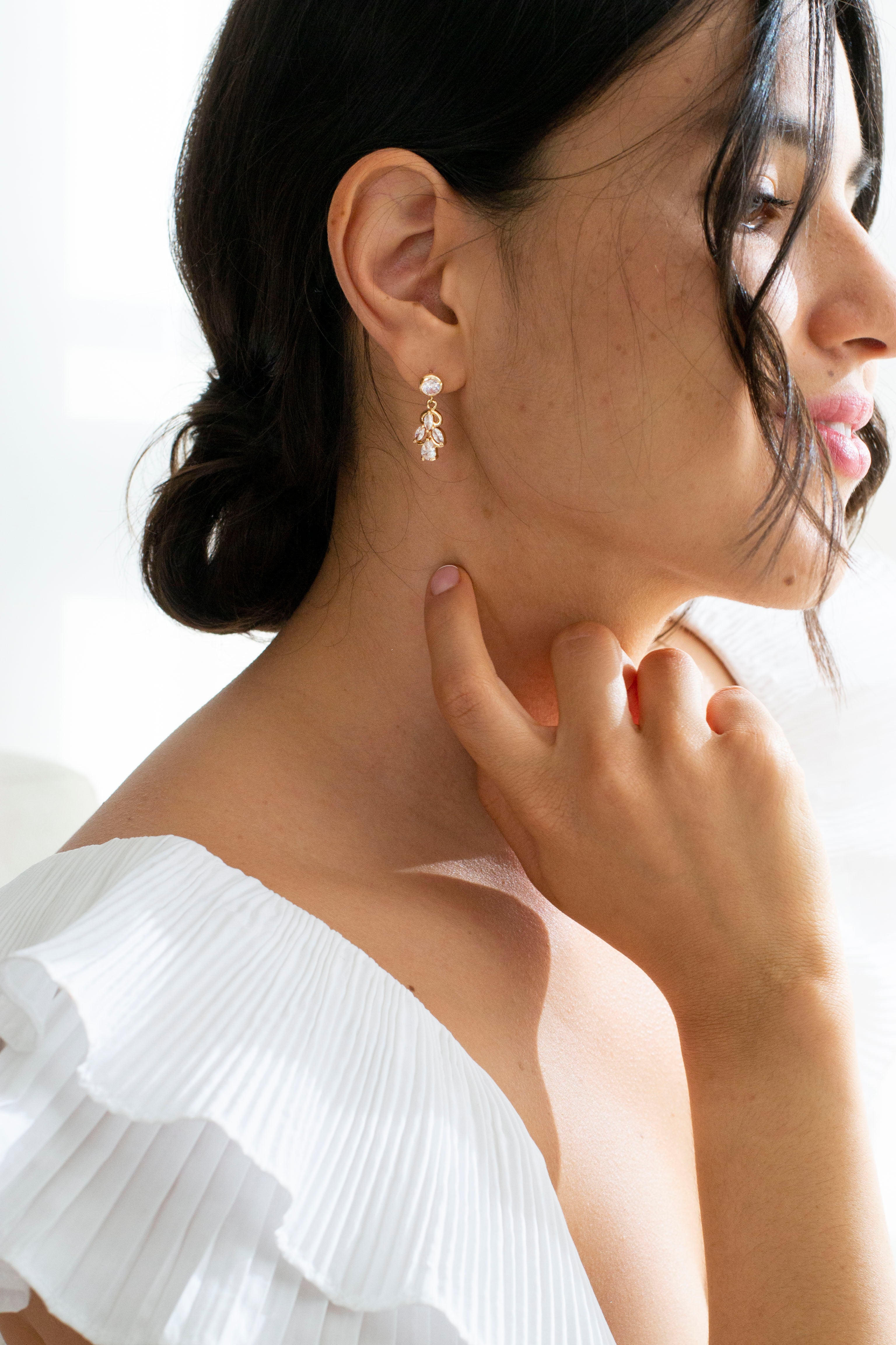 Mariée portant des boucles d'oreilles élégantes pendantes dorées à cristaux
