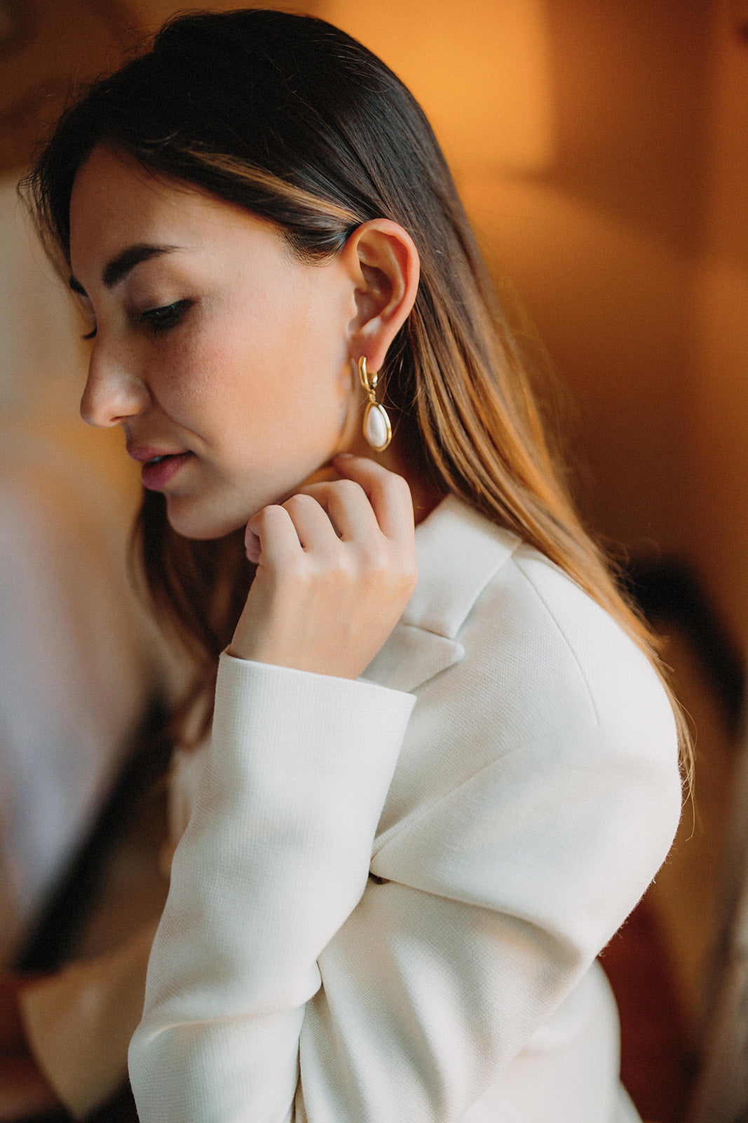 boucles d'oreilles minimaliste porté par une mariée en blazer avec les cheveux détachés qui regarde vers le sol