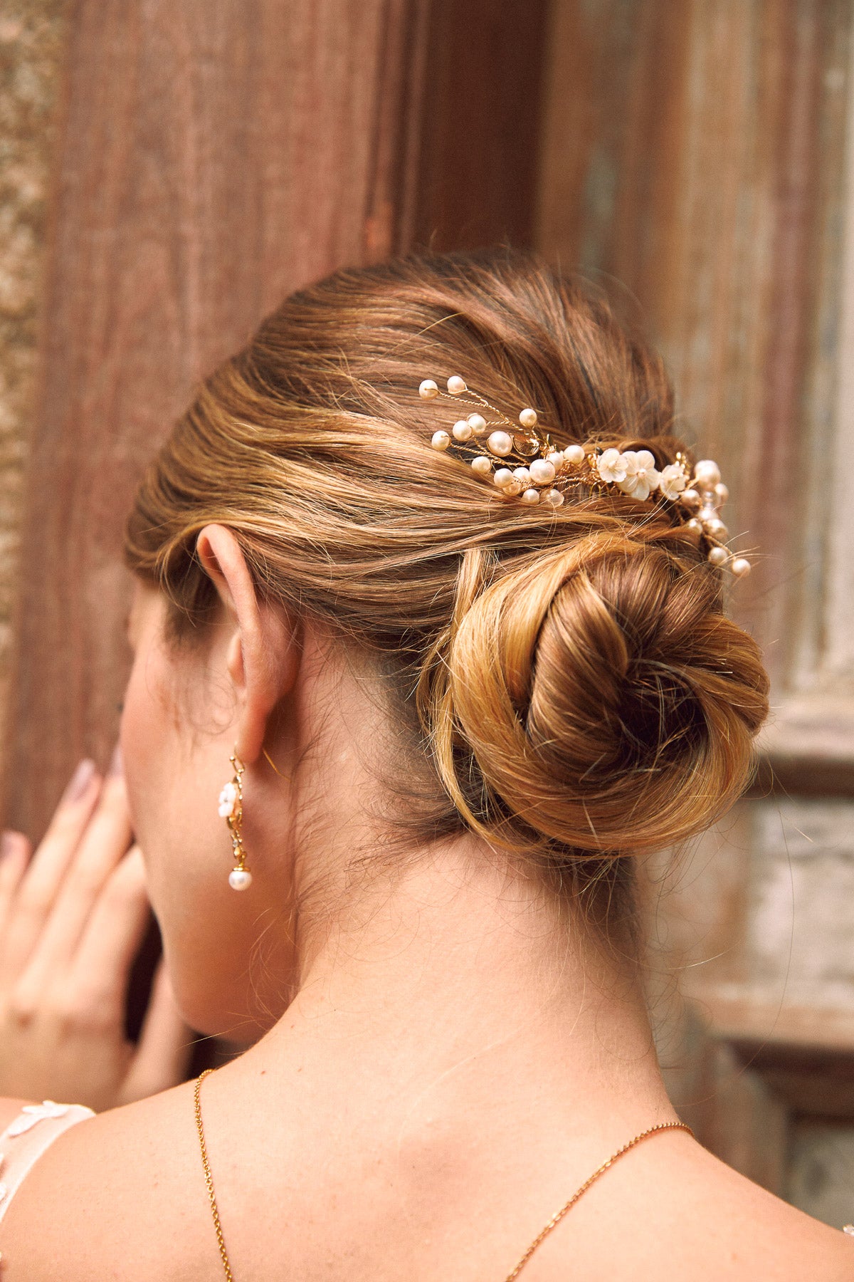 mariée coiffée avec un chignon bas et deux pic de chevaux mariage avec des perles naturelles et des boucles d'oreilles assorties