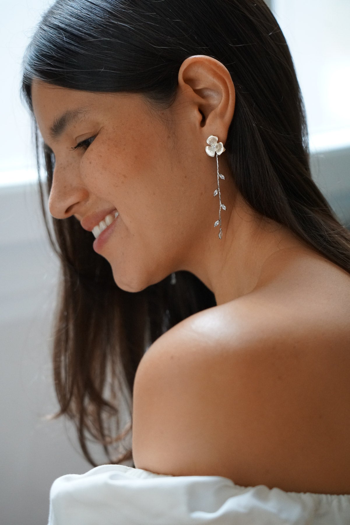 Boucles d'oreilles pendantes fleuries pour mariée bohème portée par une mariée avec les cheveux détachés