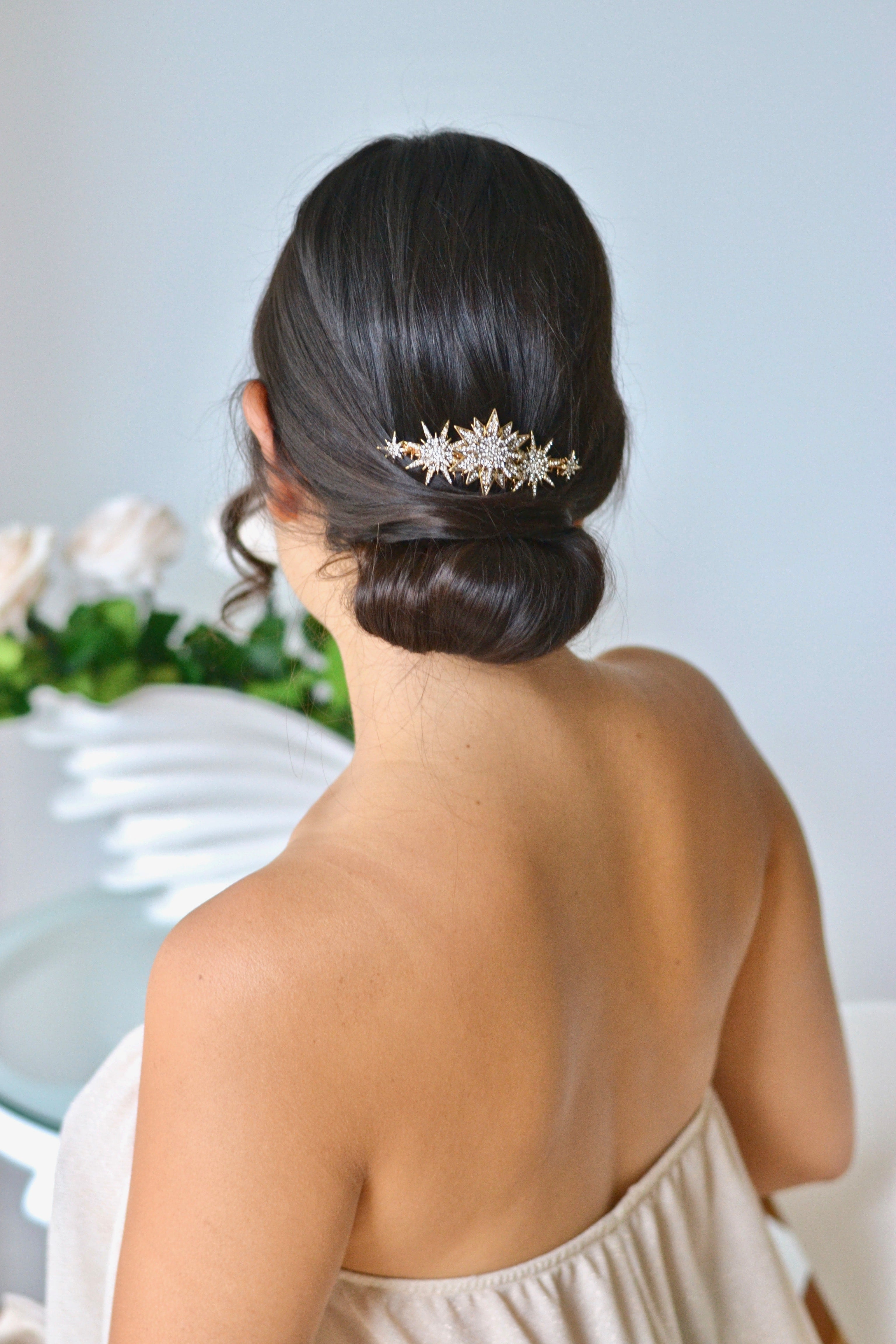 peigne céleste avec des étoiles de différentes tailles dans un chignon de mariée brune pendant les préparatifs de son mariage bohème