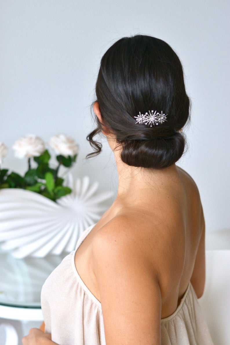 mariée coiffée pour le jour de son mariage avec un chignon bas et un peigne mariage céleste avec 3 étoiles