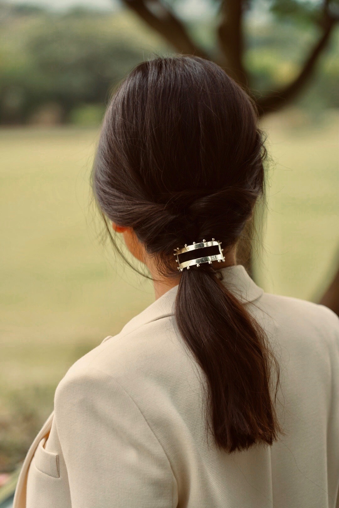 mariée le jour du mariage avec blazer blanc coiffée avec une queue de cheval bas et un élastique en argent bohème
