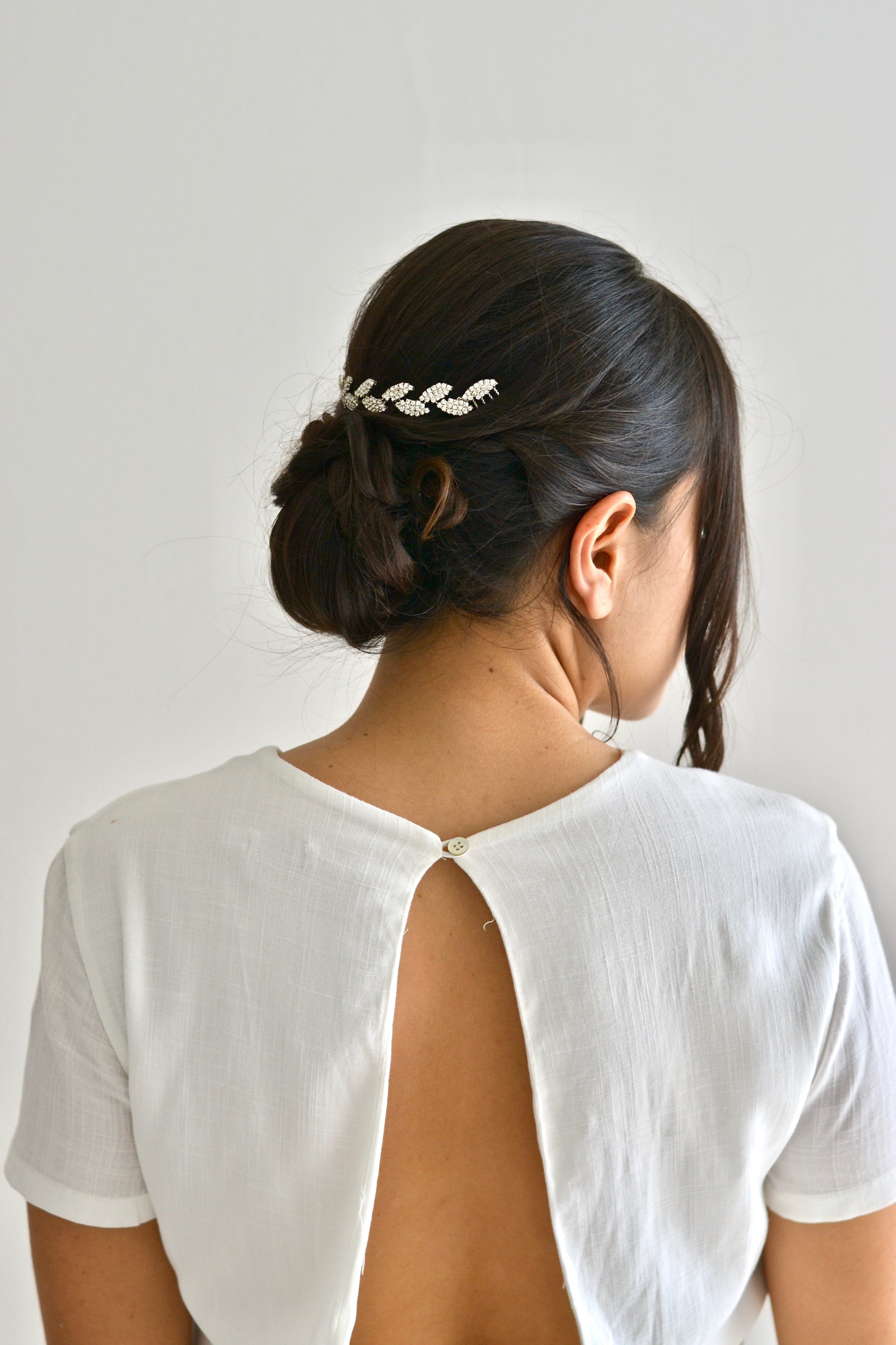 Mariée chignon élégant portant une vigne de cheveux en feuilles argentées et cristaux