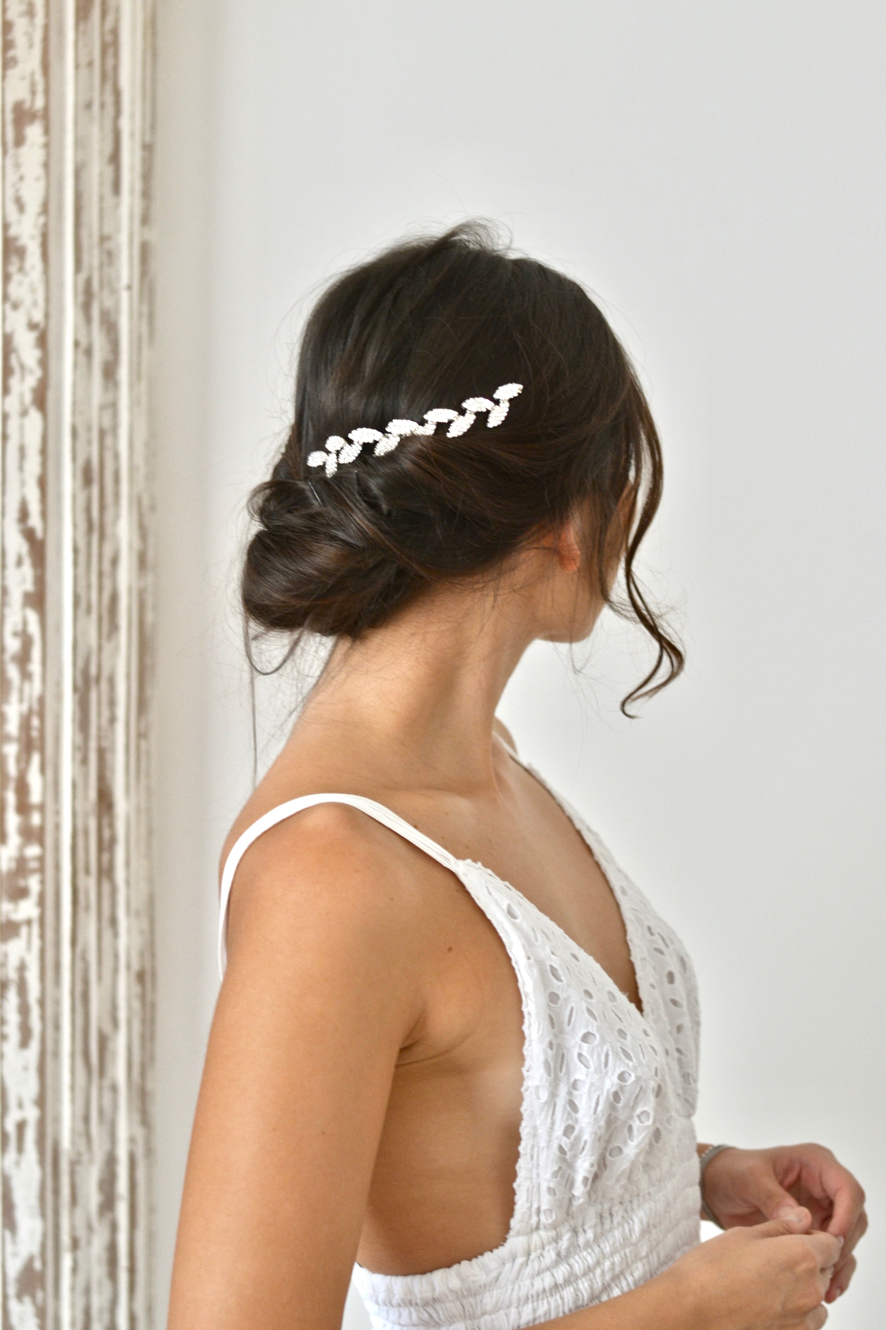 Mariée avec coiffure bohème portant une vigne de cheveux en feuilles argentées et cristaux