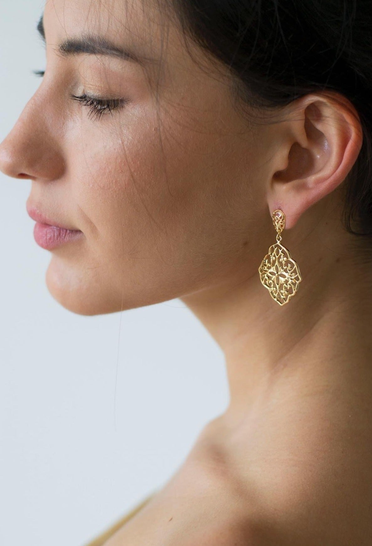 Mariée portant des boucles d'oreilles pendantes ornementales dorées