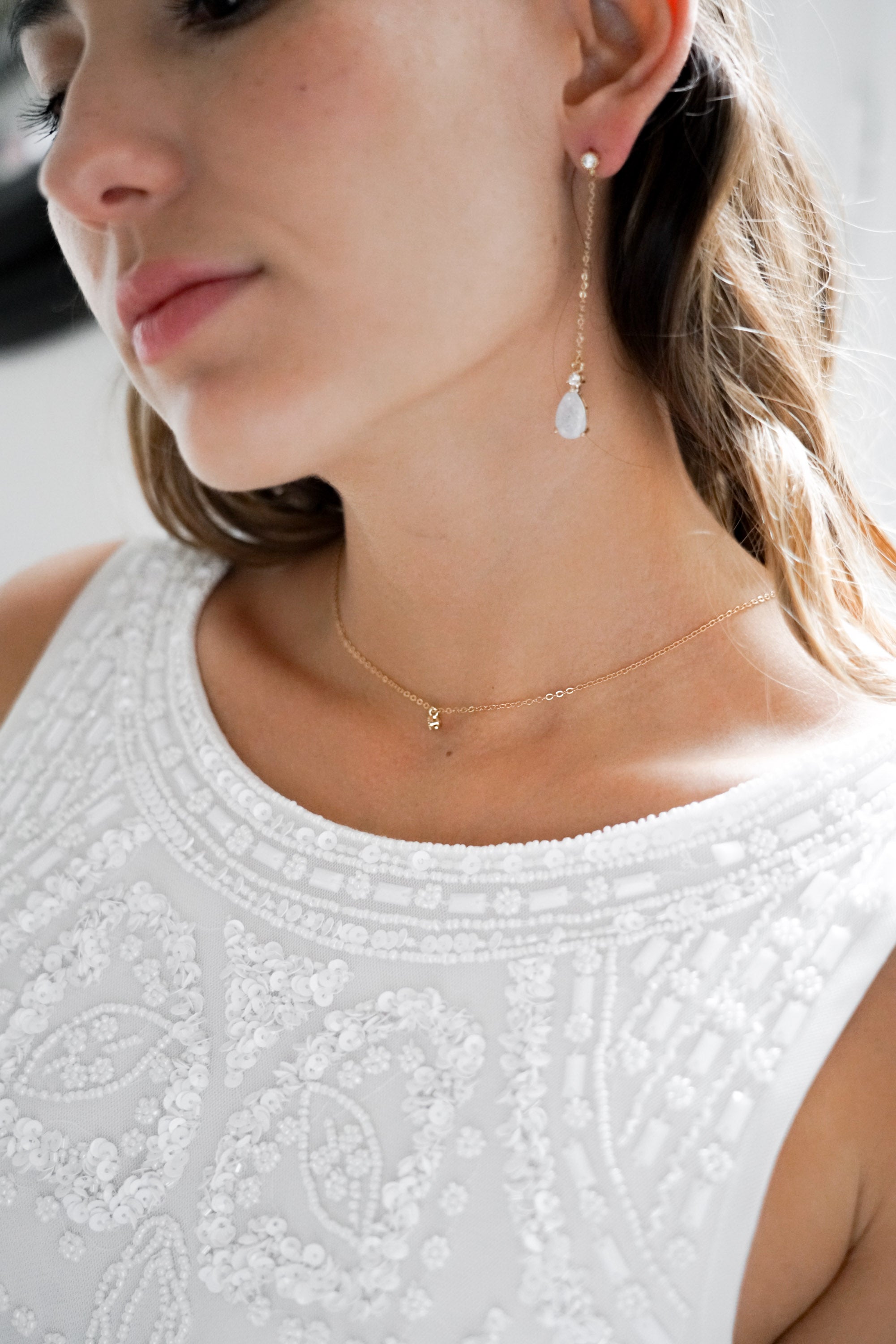 boucles d'oreilles pendantes mariage avec une chaine et un cristaux porté avec un collier de mariage en or