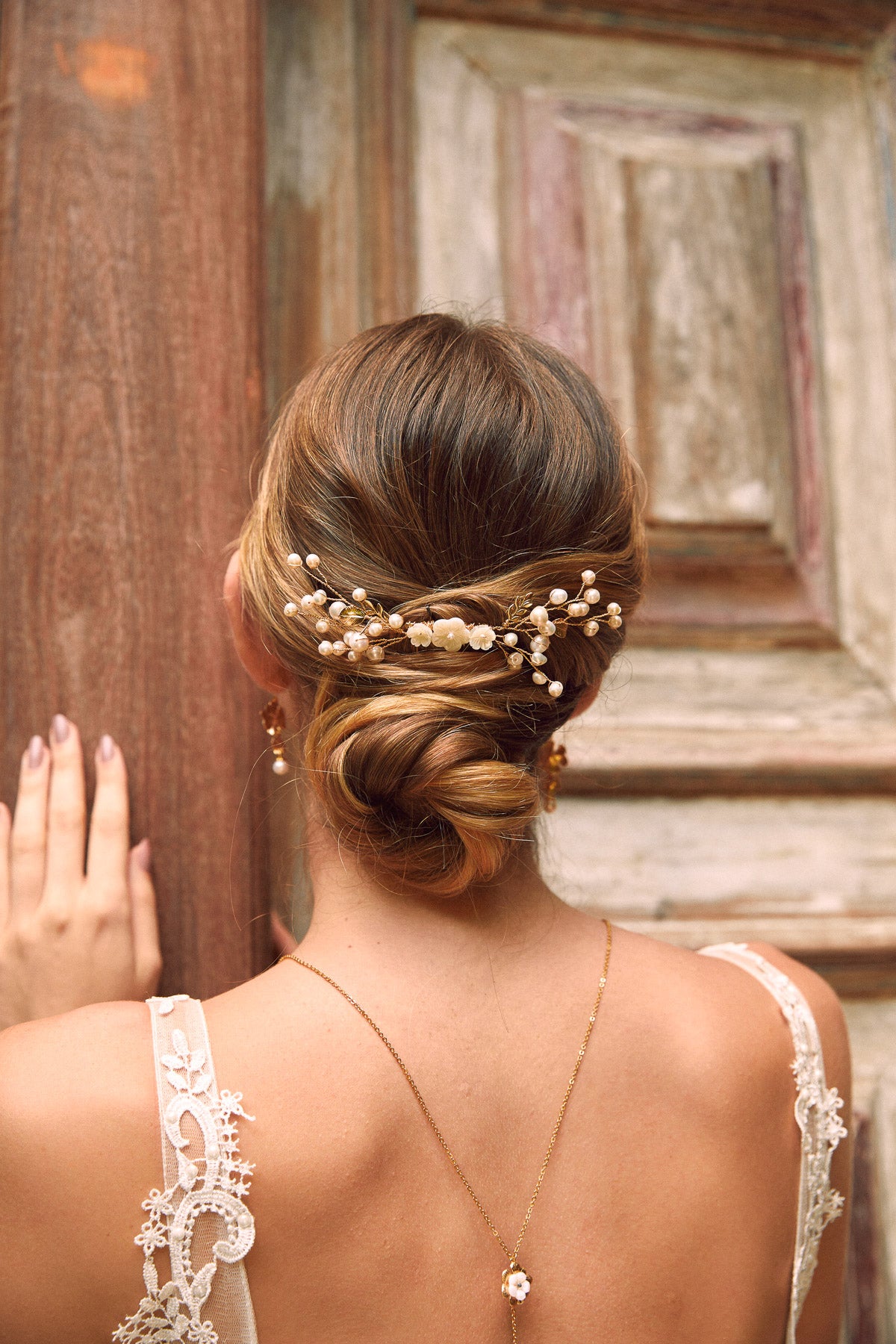 mariée coiffée avec un chignon bas et deux pic de chevaux mariage avec des perles naturelles et des petites fleurs en nacre