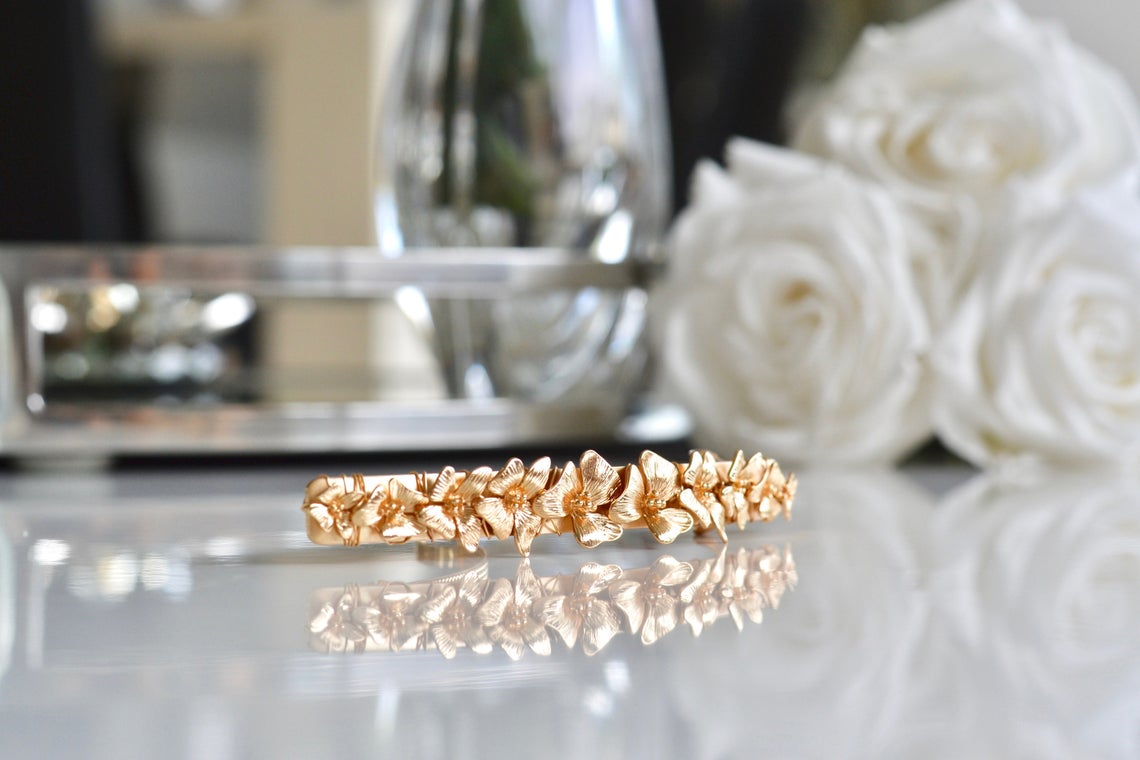 Barrette florale couleur or devant des roses blanches