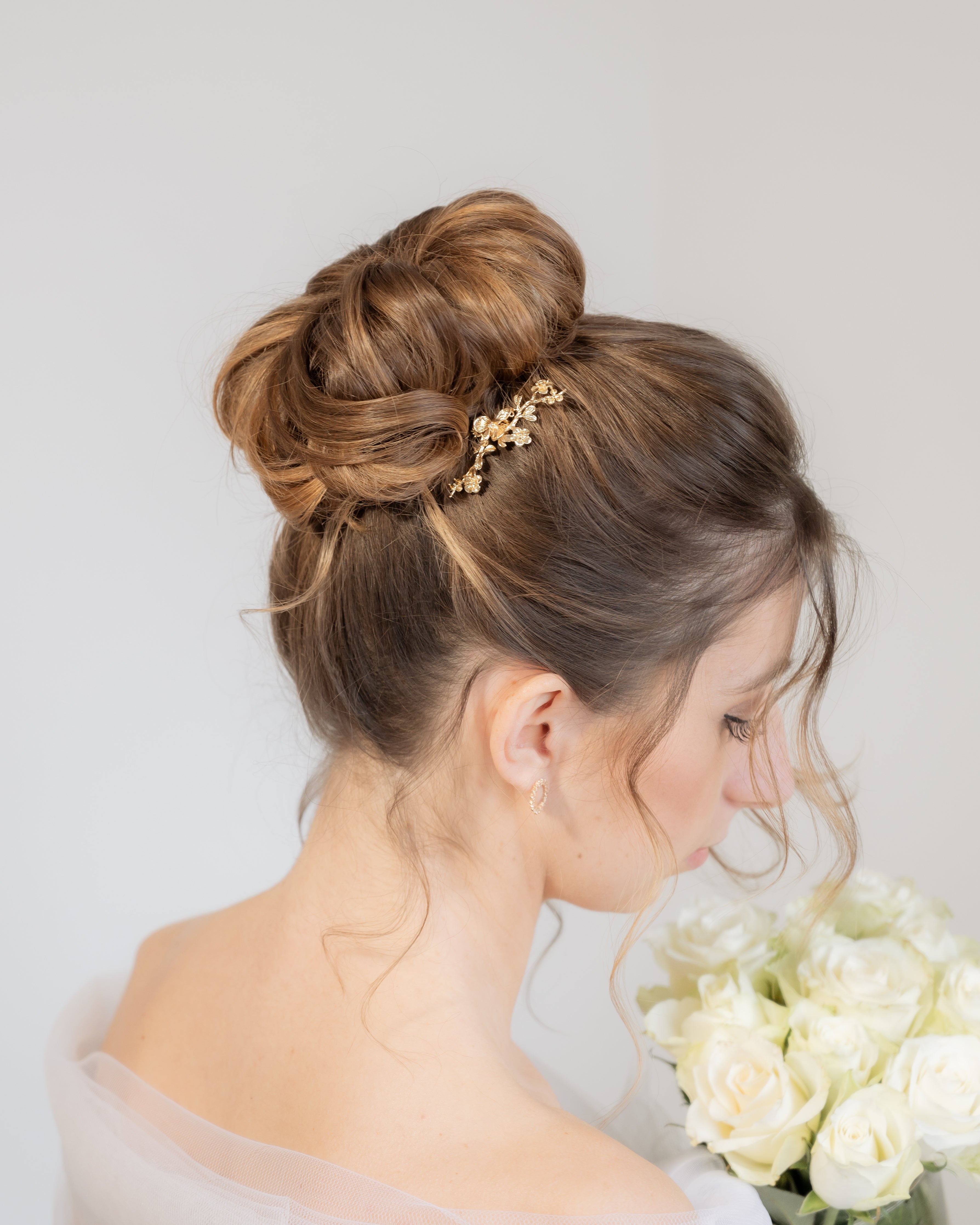 Mariée élégante avec chignon haut accessoirisé d'un petit pic à cheveux fleuri
